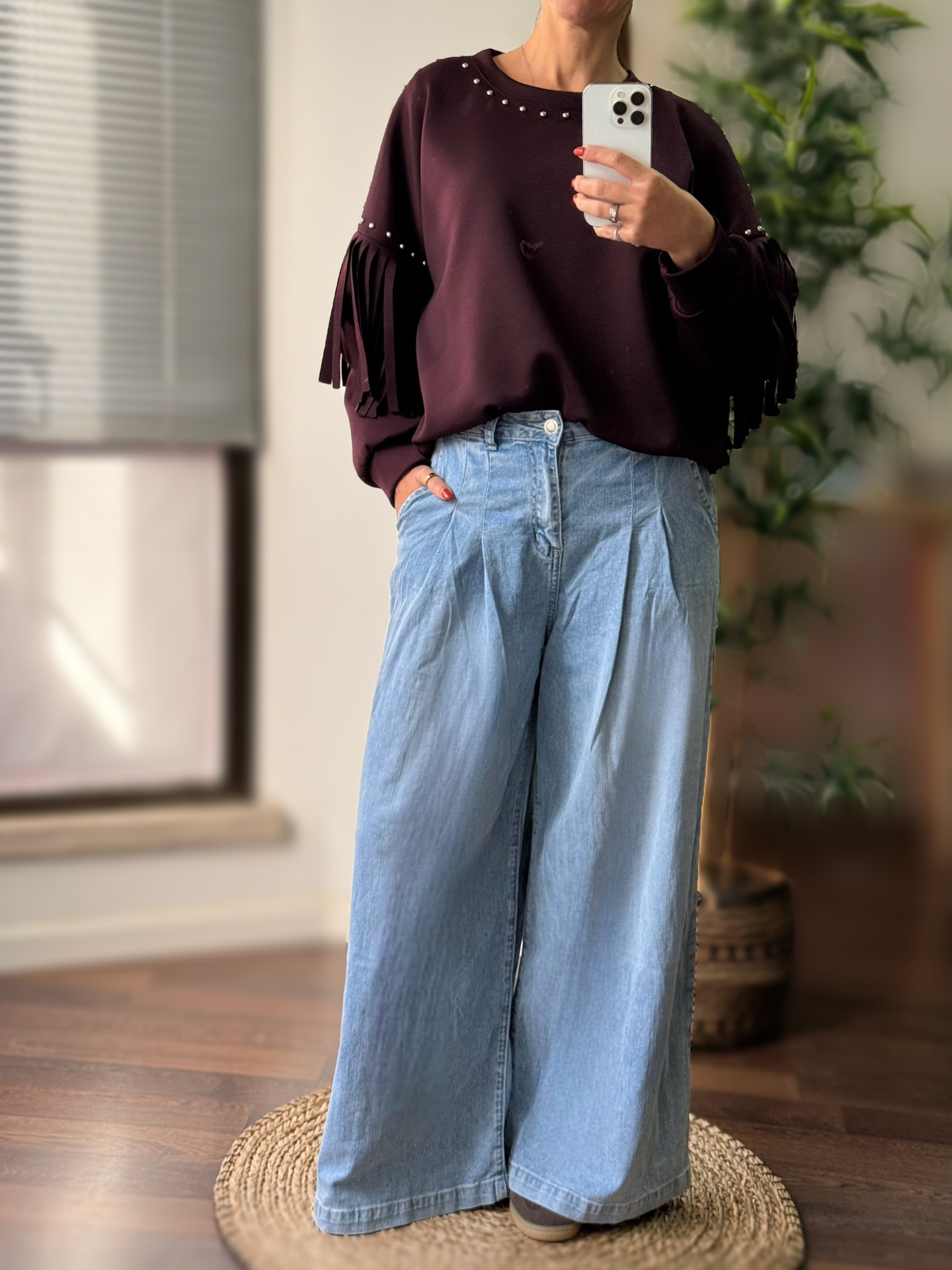 Top bordeaux com franjas e pérolas e calças largas azul claro em ambiente interior
