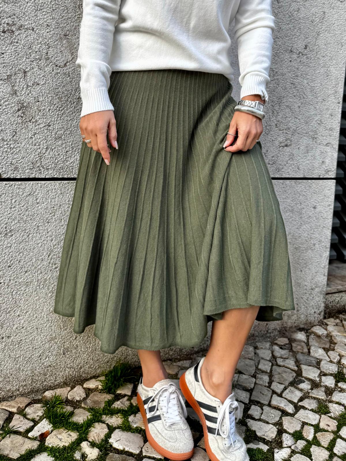 Saia verde plissada com camisola branca e ténis brancos