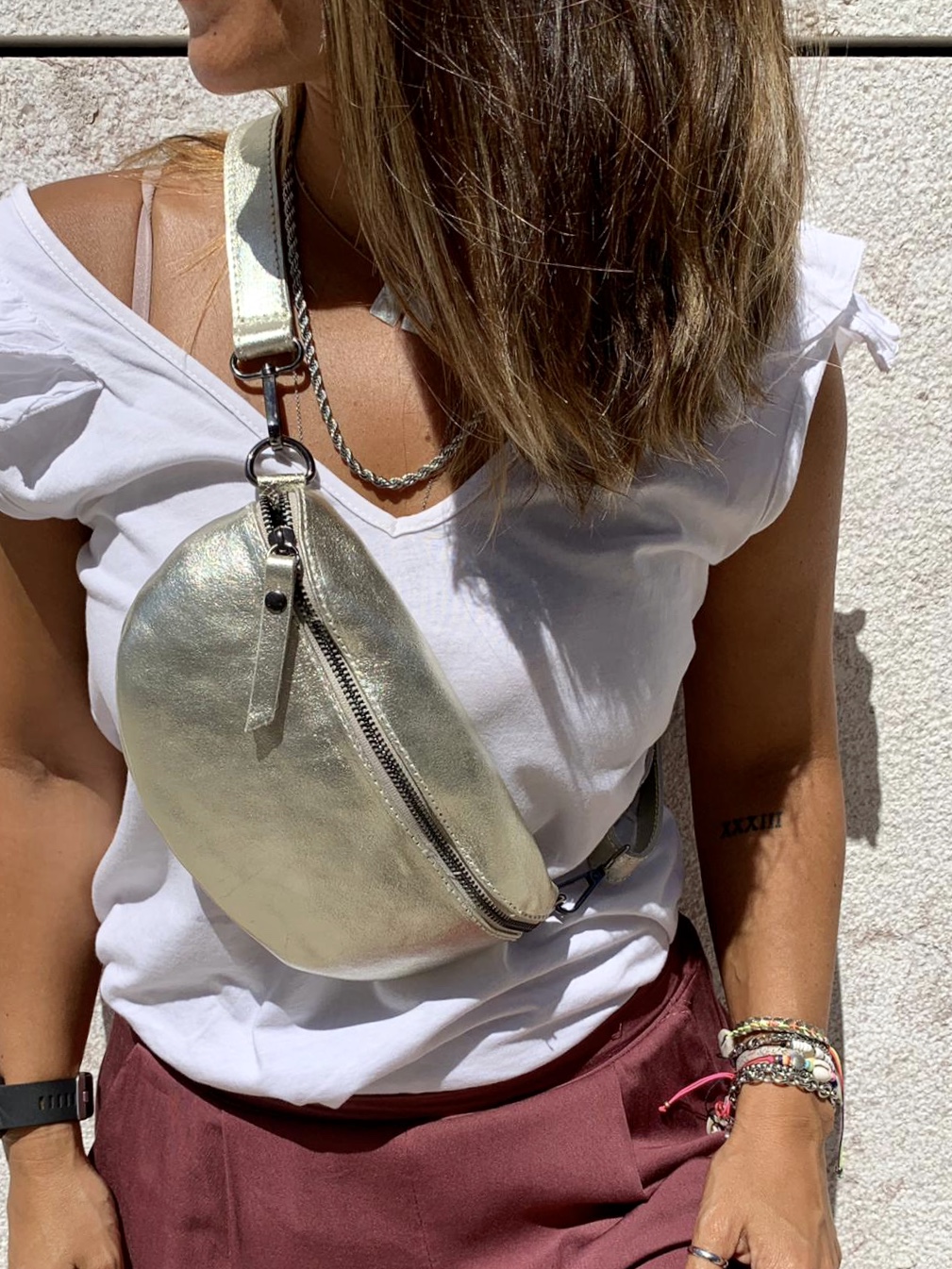 Mala pochete dourada de pele usada cruzada com roupa casual