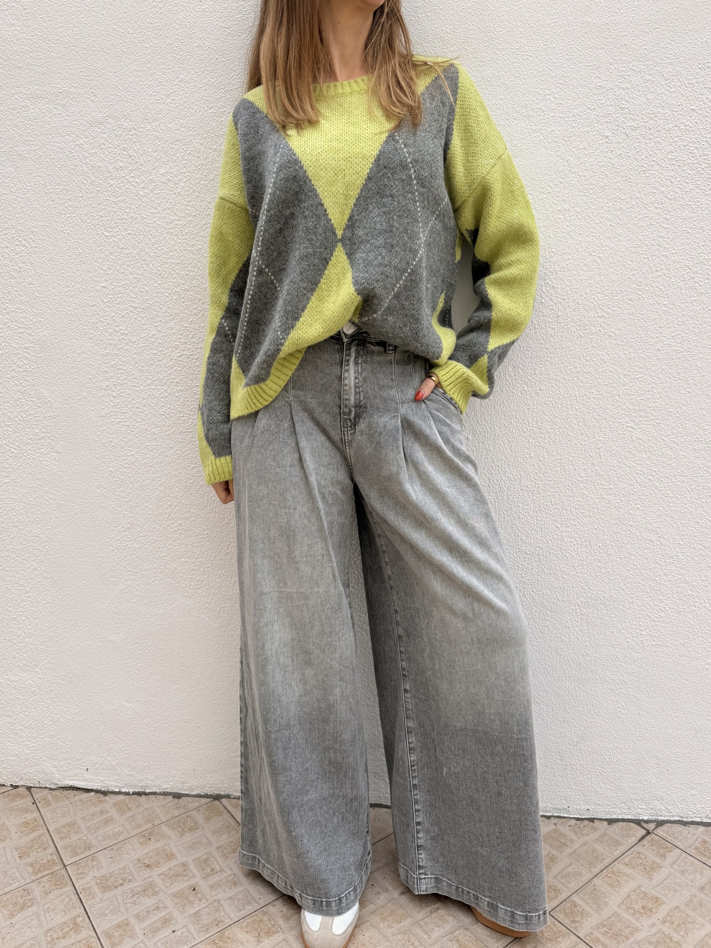 Camisola de malha amarelo e cinzenta com padrão de losangos e calças largas cinzentas de ganga