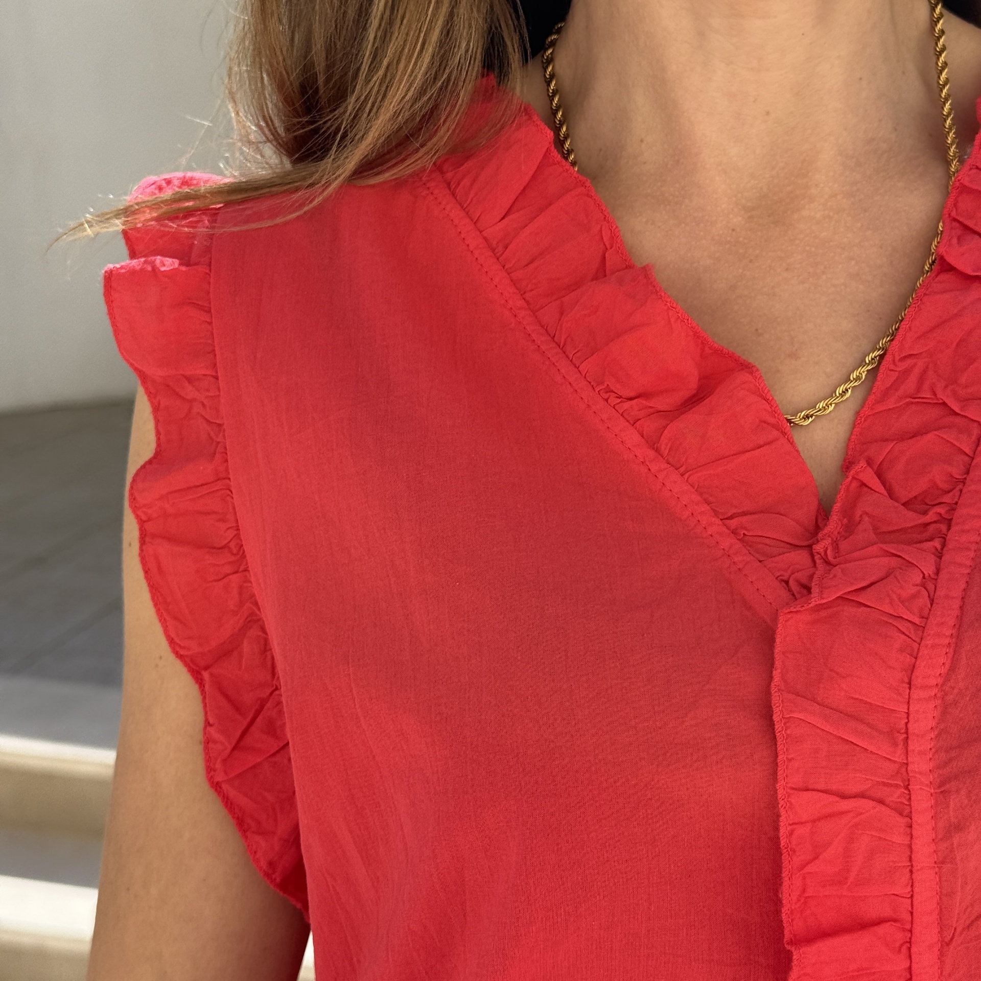 Blusa vermelha com babados e colar dourado torcido