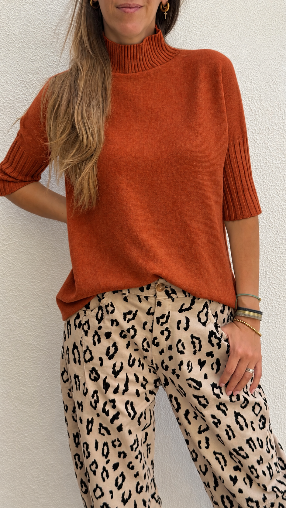 Camisola laranja de malha com gola alta e calças bege animal print.