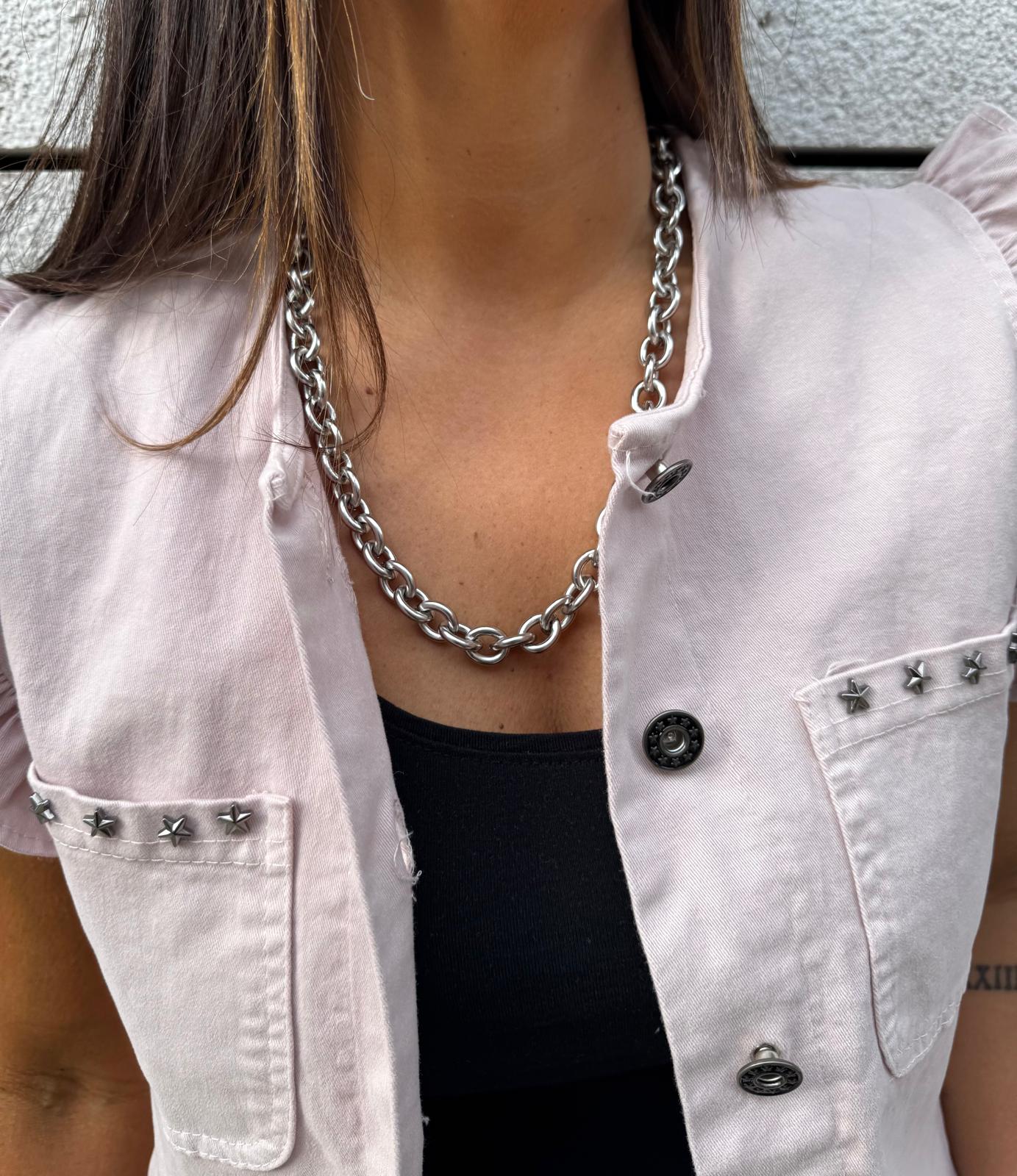 Colar de elos grandes em metal prateado com colete rosa claro e tachas metálicas.