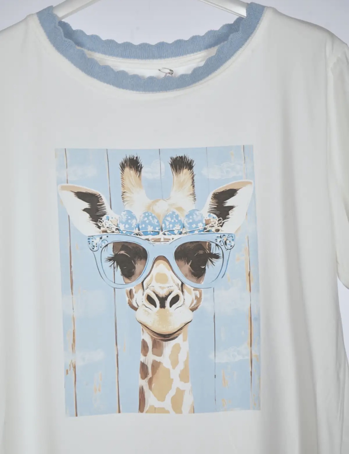 T-shirt branca com estampa de girafa com óculos azul e coroa de ovos azuis