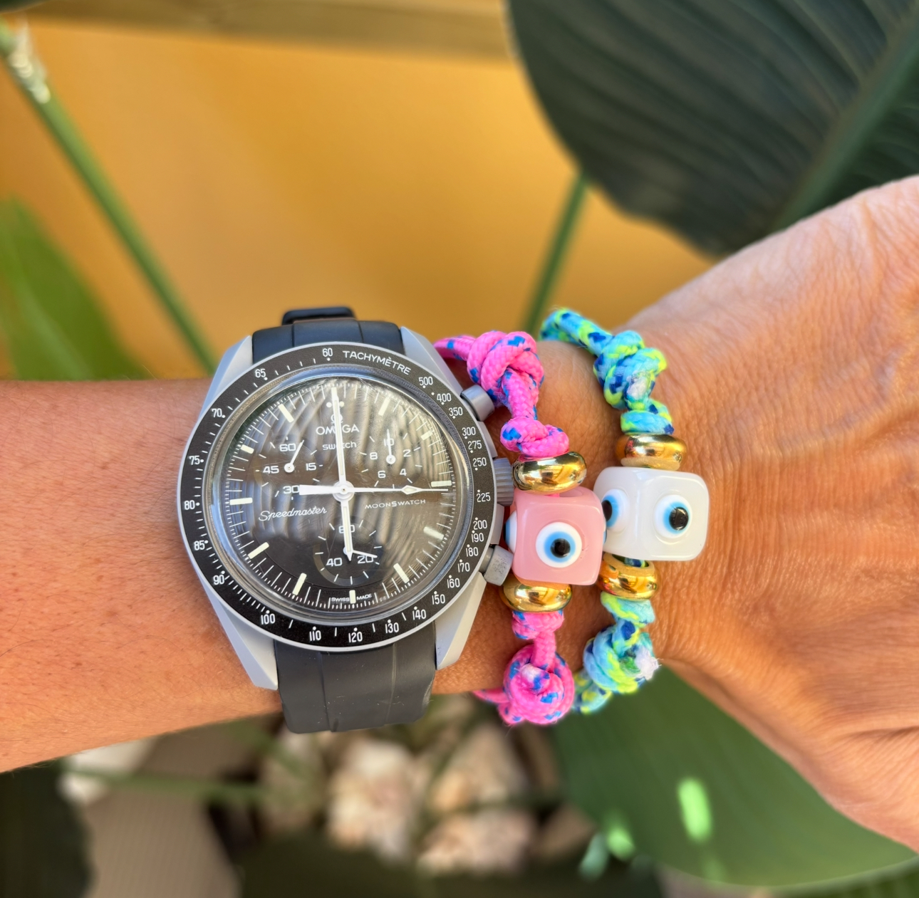 Relógio preto com pulseira de borracha e duas pulseiras coloridas no pulso