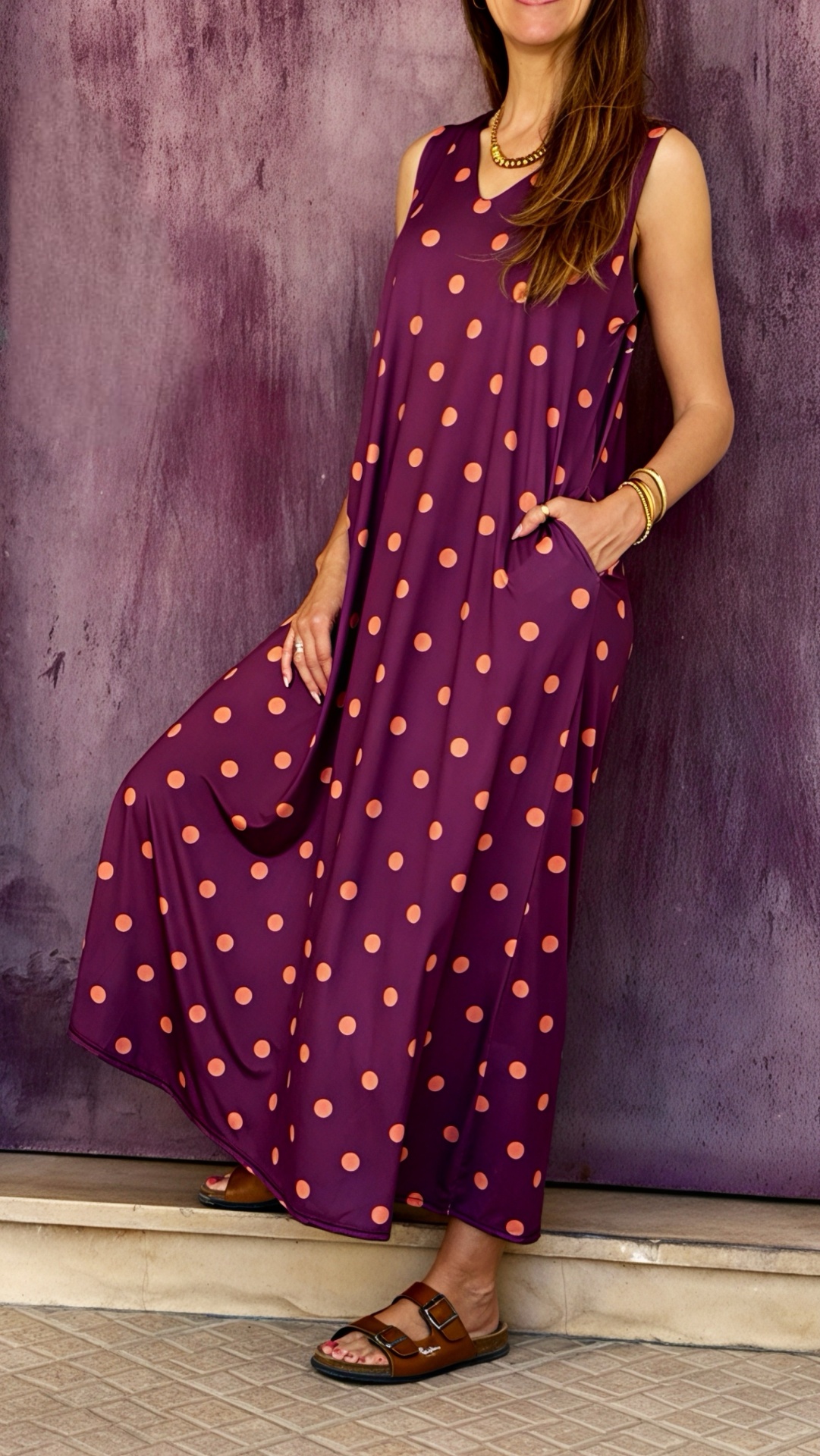 Vestido longo sem mangas roxo com bolinhas cor de salmão e sandálias castanhas.