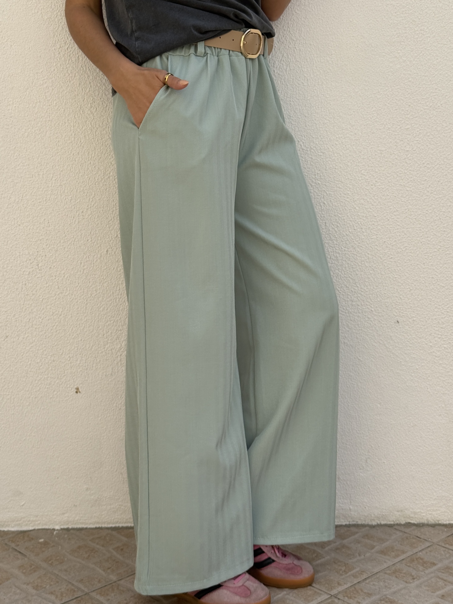 Calças verdes largas com cinto bege e ténis rosa