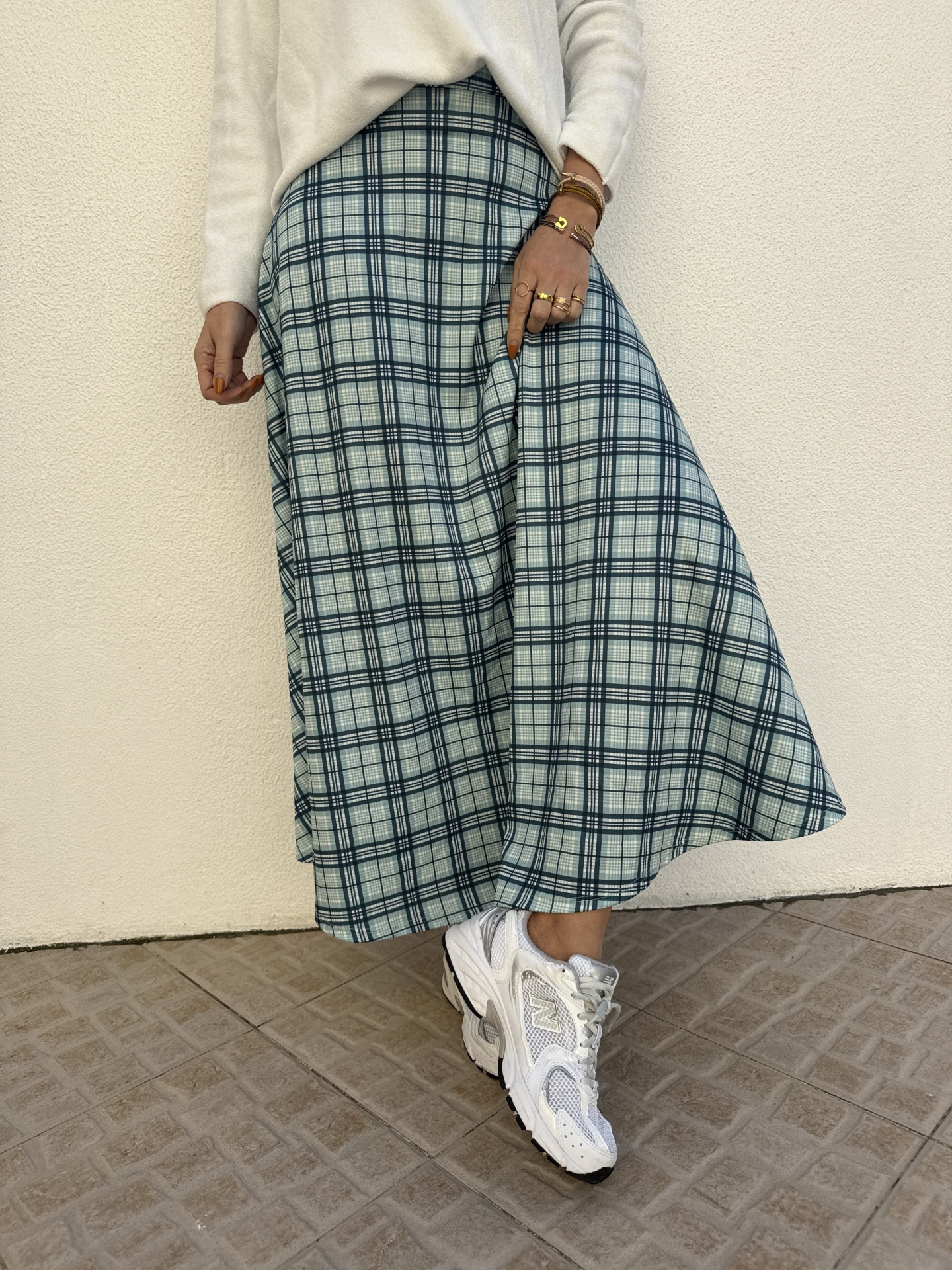 Saia xadrez azul e branca combinada com camisola branca e ténis brancos New Balance