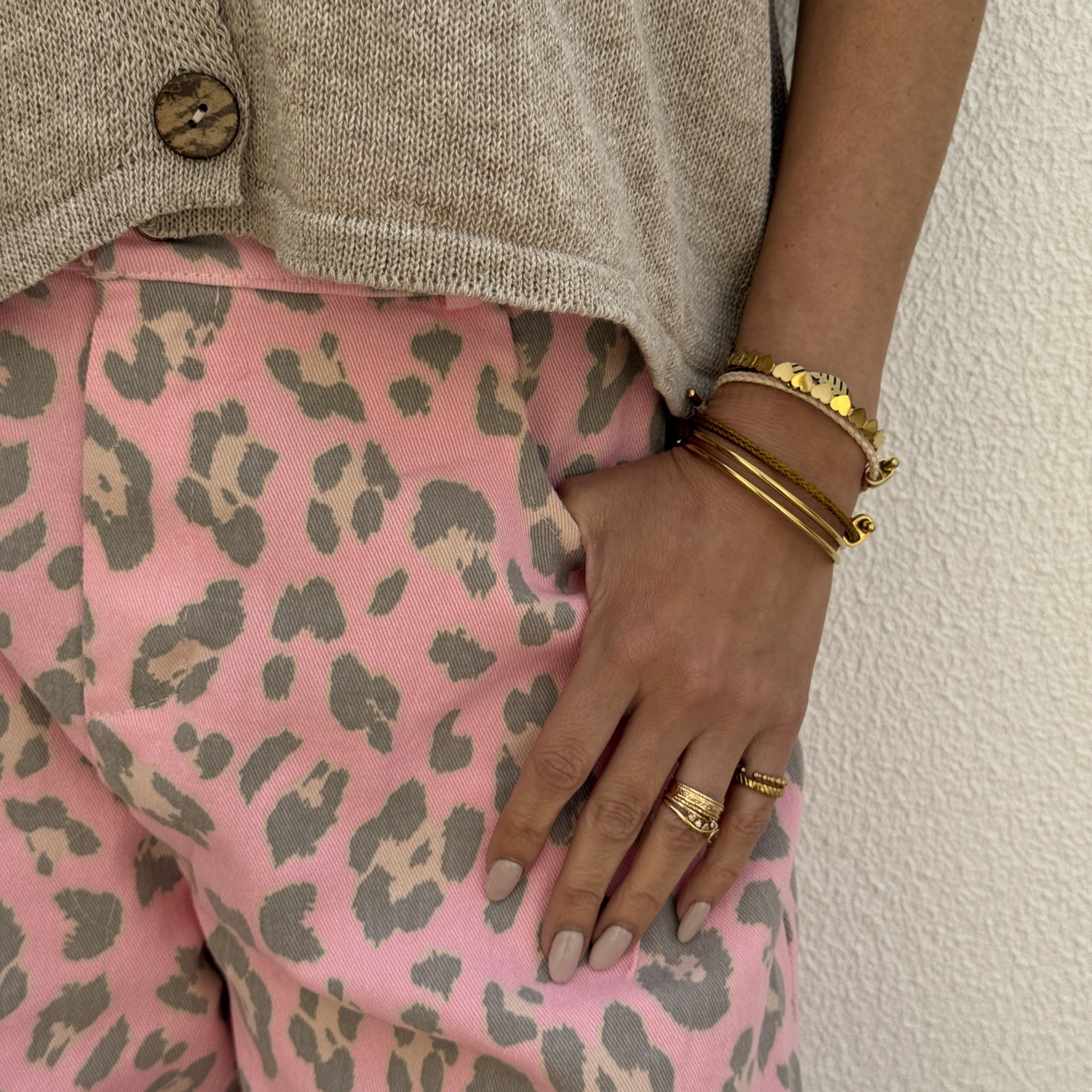 Calças rosa estampadas e camisola bege com acessórios dourados