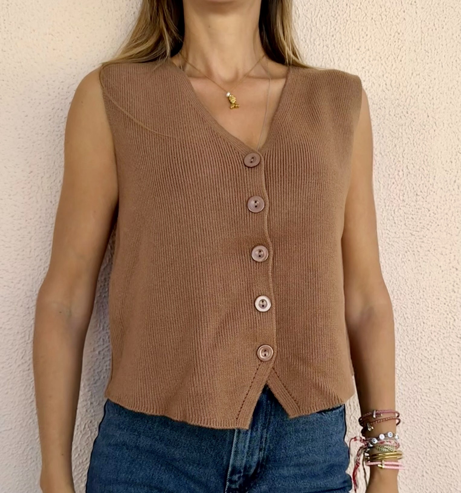 Colete de malha castanho claro com botões frontais usados com calças de ganga azuis