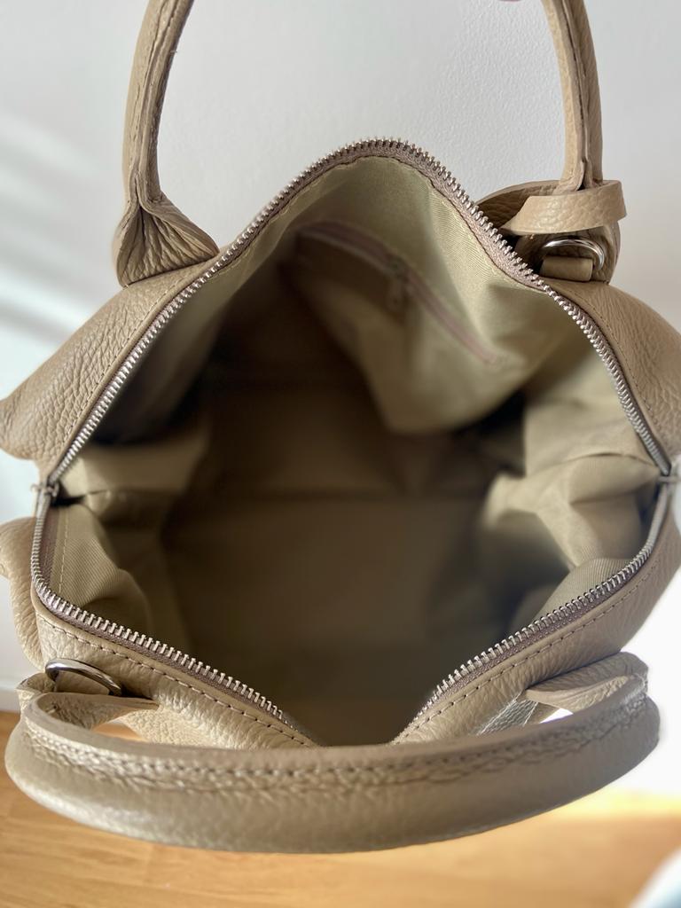 Bolsa de mão bege em pele com interior forrado aberto e alça visível