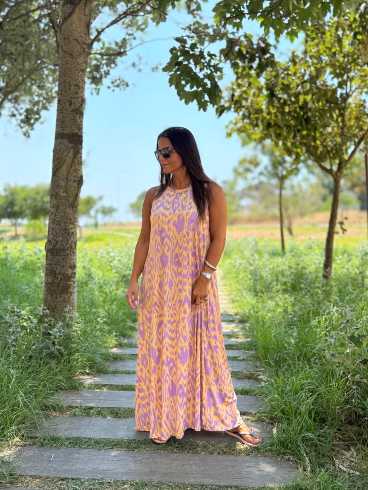 Vestido comprido lilás e amarelo em mulher num parque com árvores