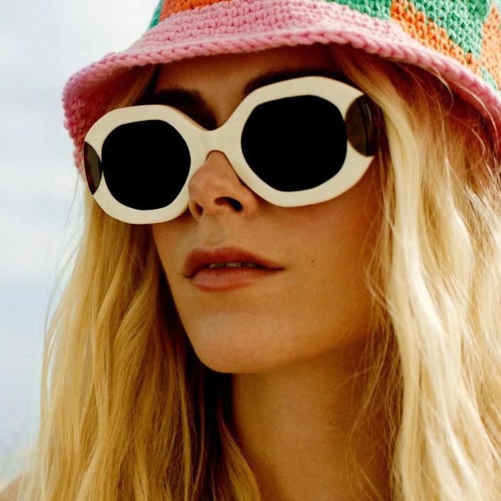 Mulher com óculos de sol brancos e chapéu de crochê colorido