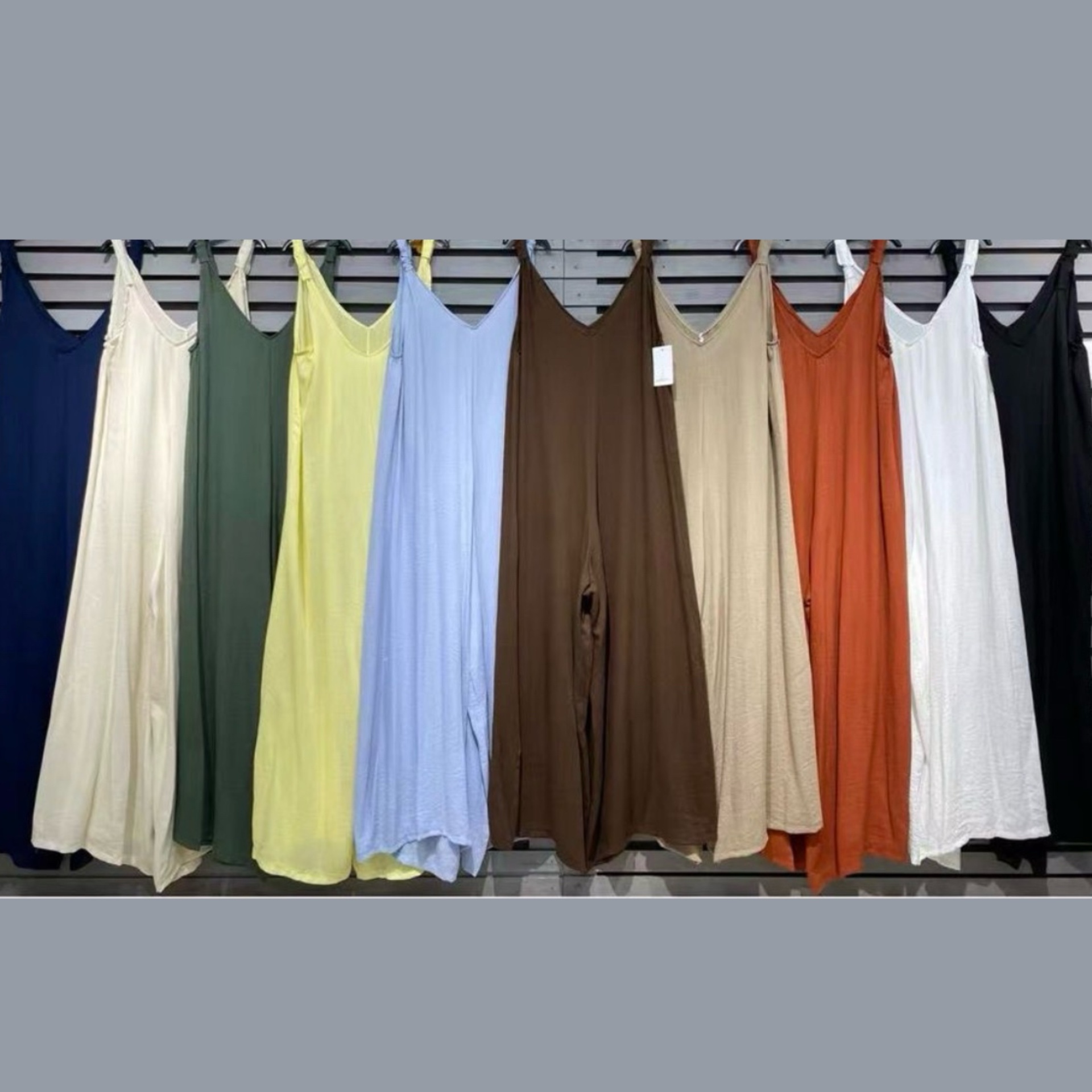 Vestidos compridos coloridos pendurados numa parede de ripas.