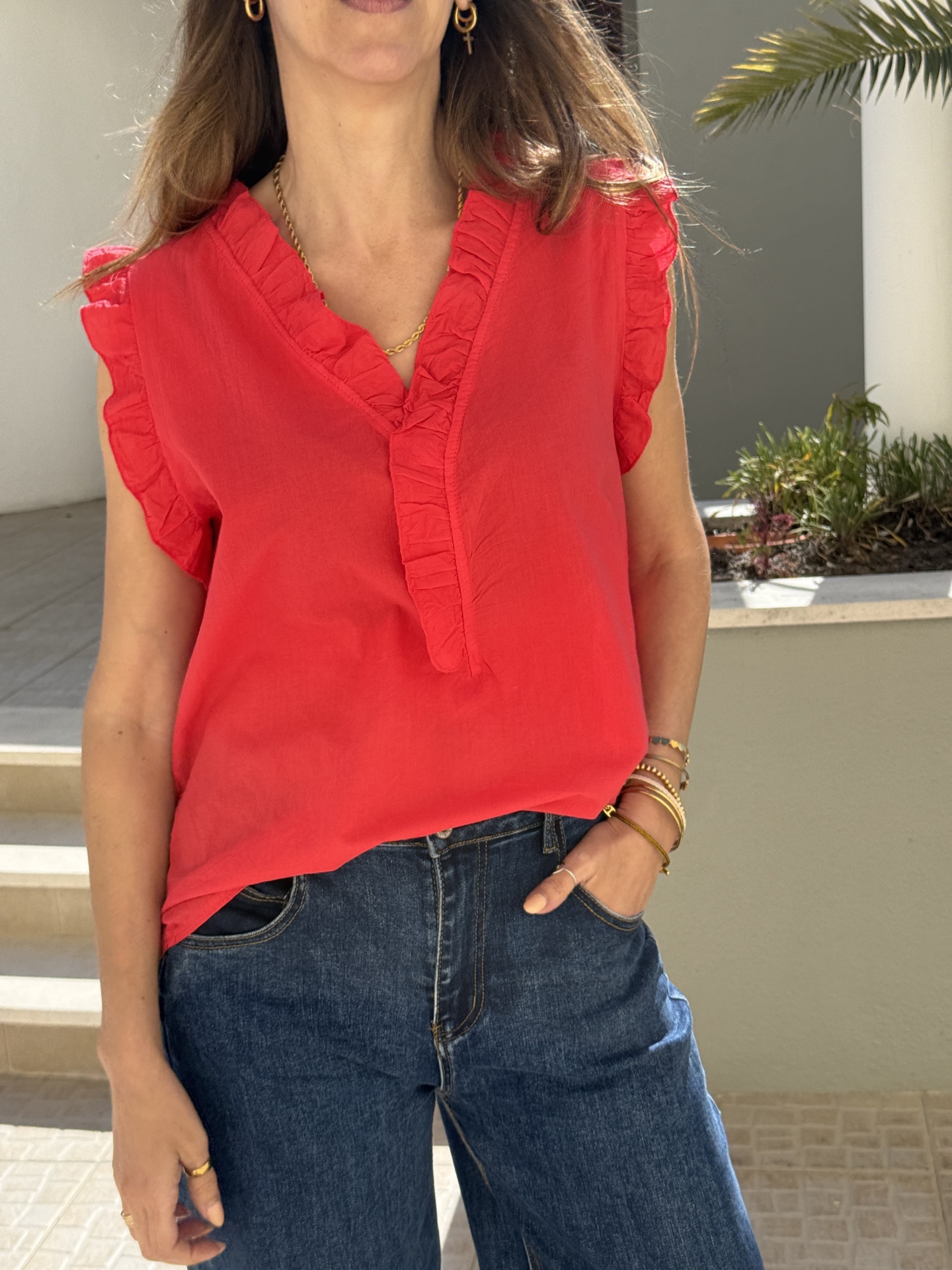 Blusa vermelha com folhos e calças de ganga azul escuro