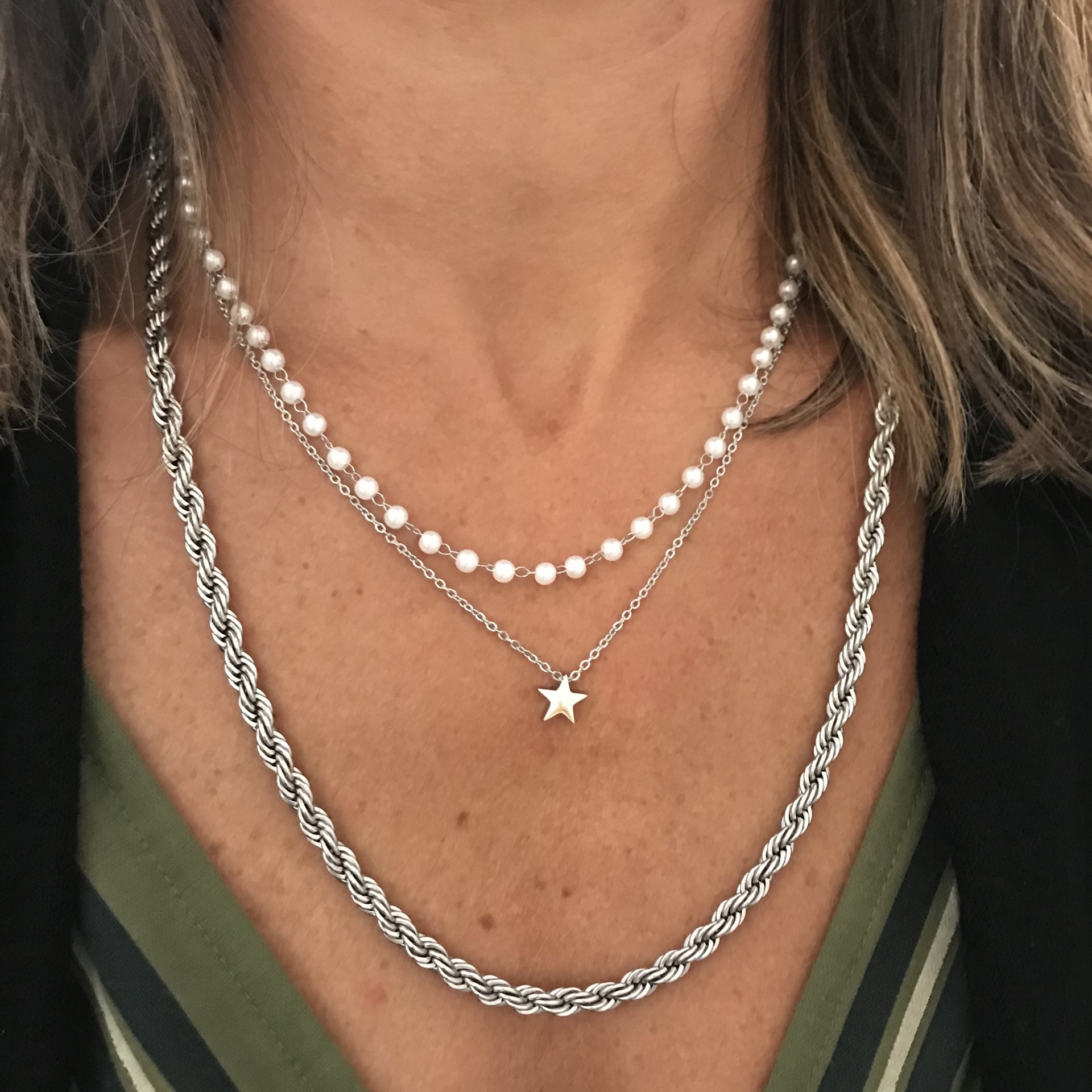 Colares de pérolas e prata com pendente de estrela no pescoço de pessoa