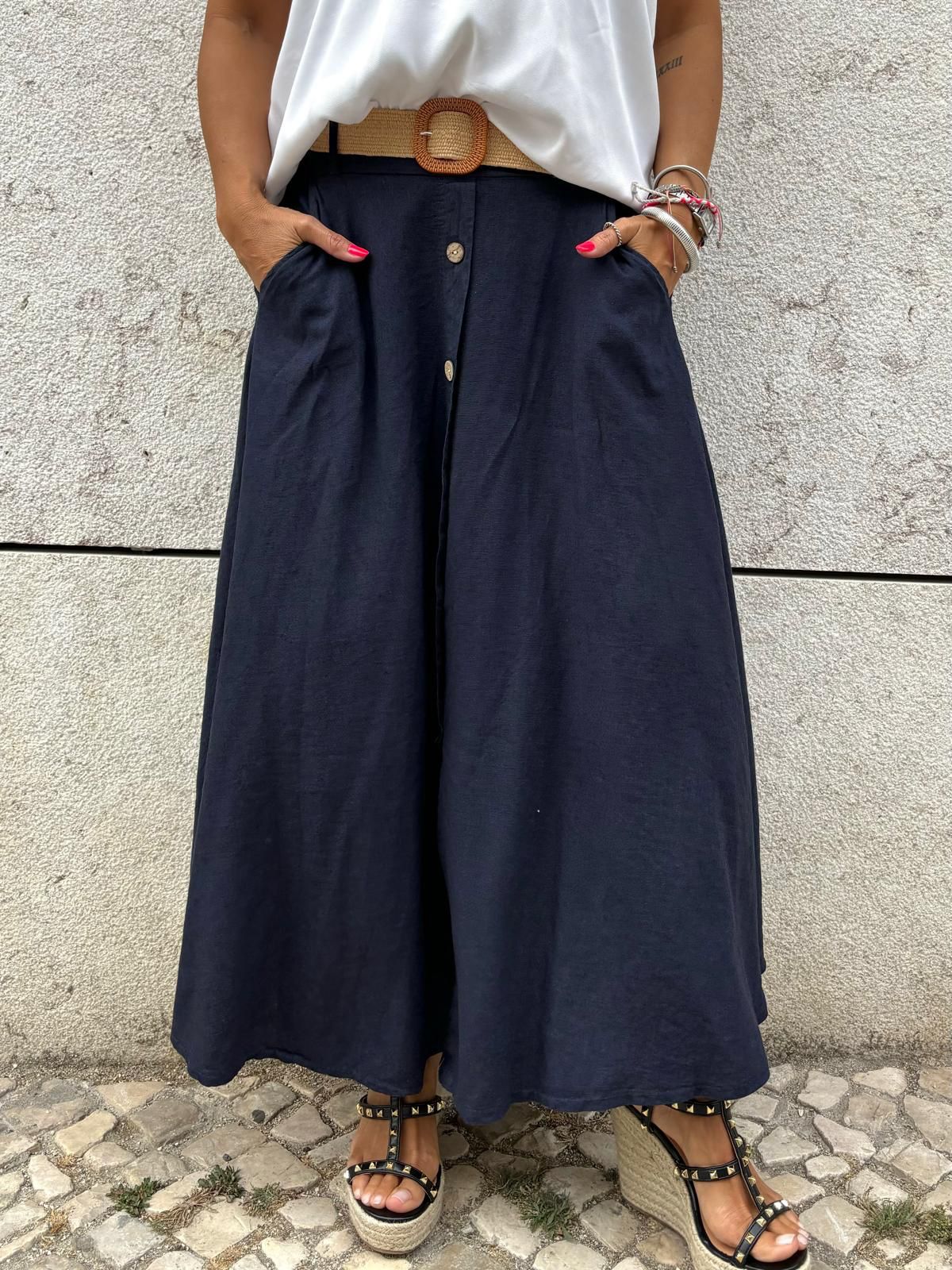 Calças largas azul escuro com botões e bolsos, cinto castanho, sandálias de salto pretas com tachas