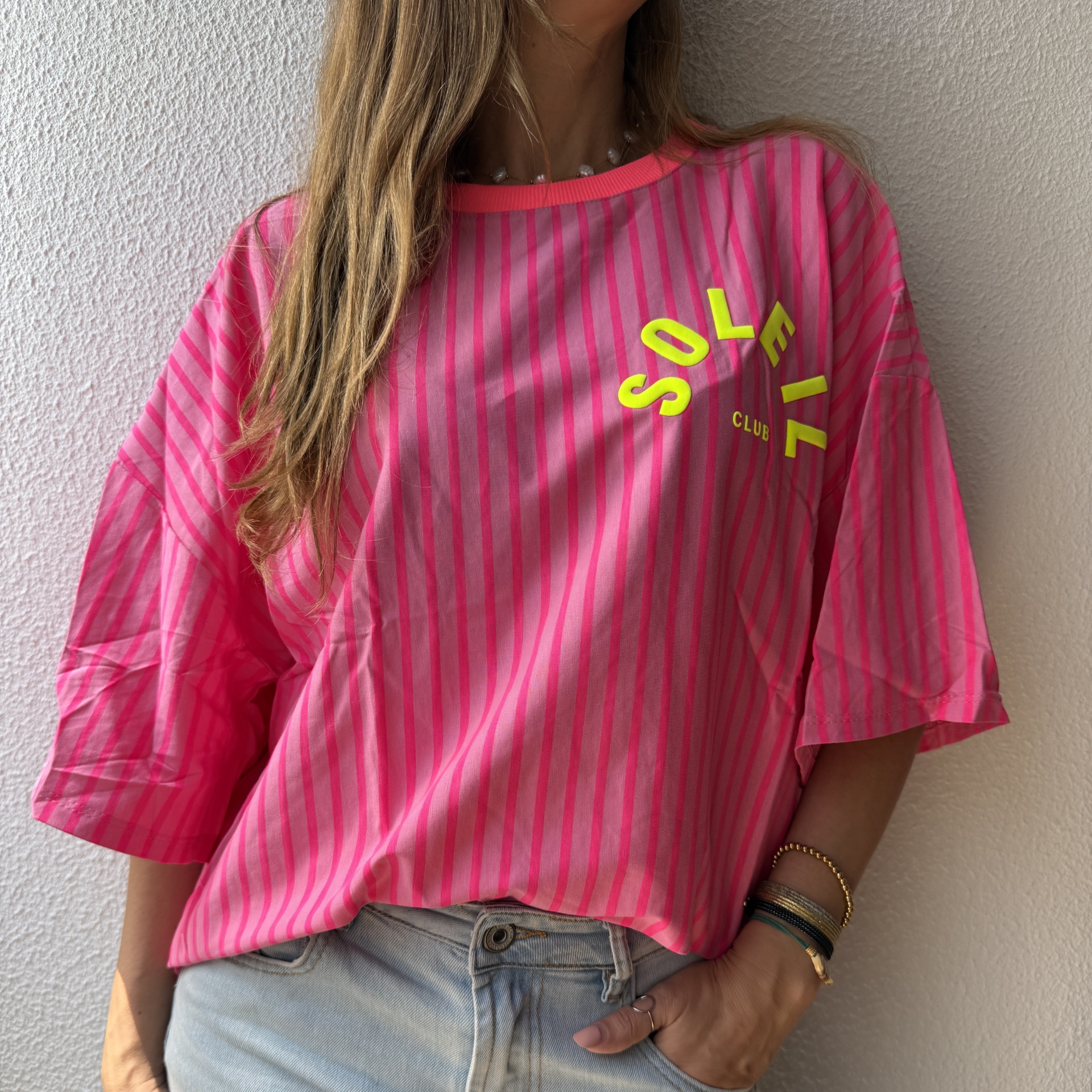T-shirt rosa riscada com texto amarelo fluorescente e calças de ganga claras