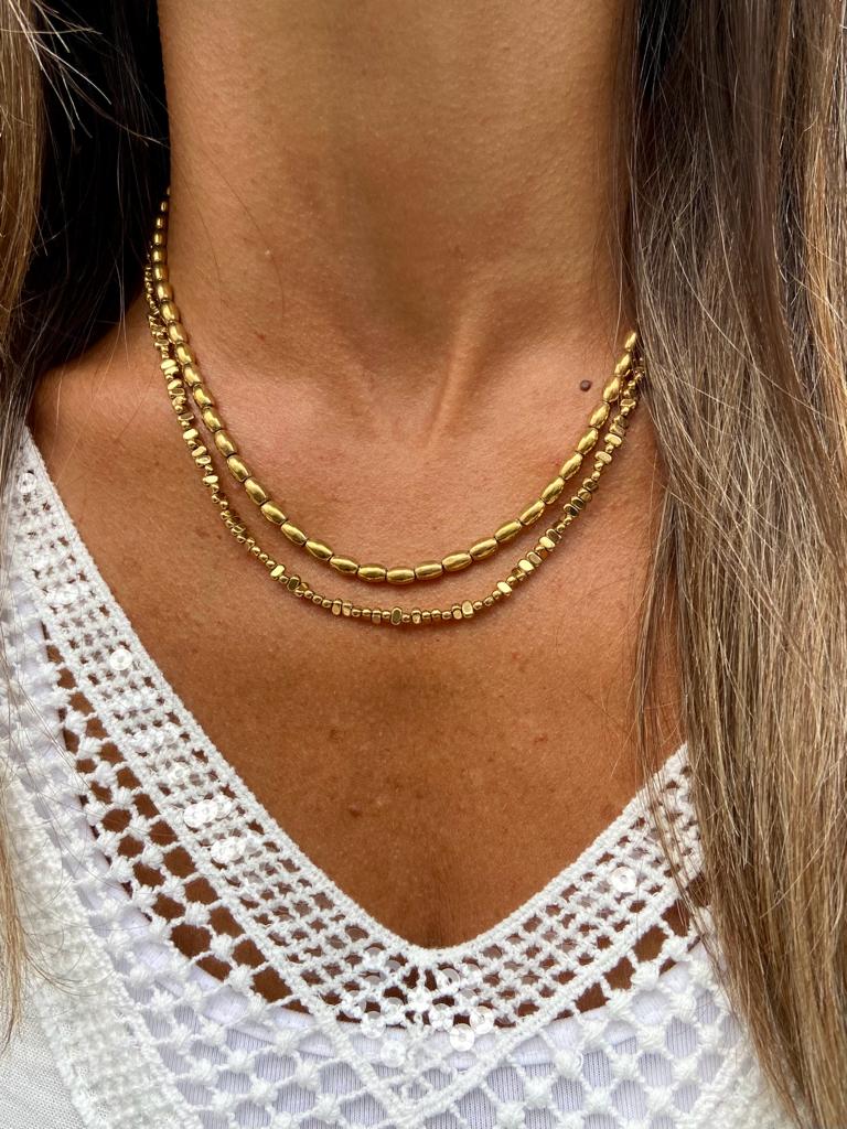Colar duplo dourado com contas e blusa branca rendada
