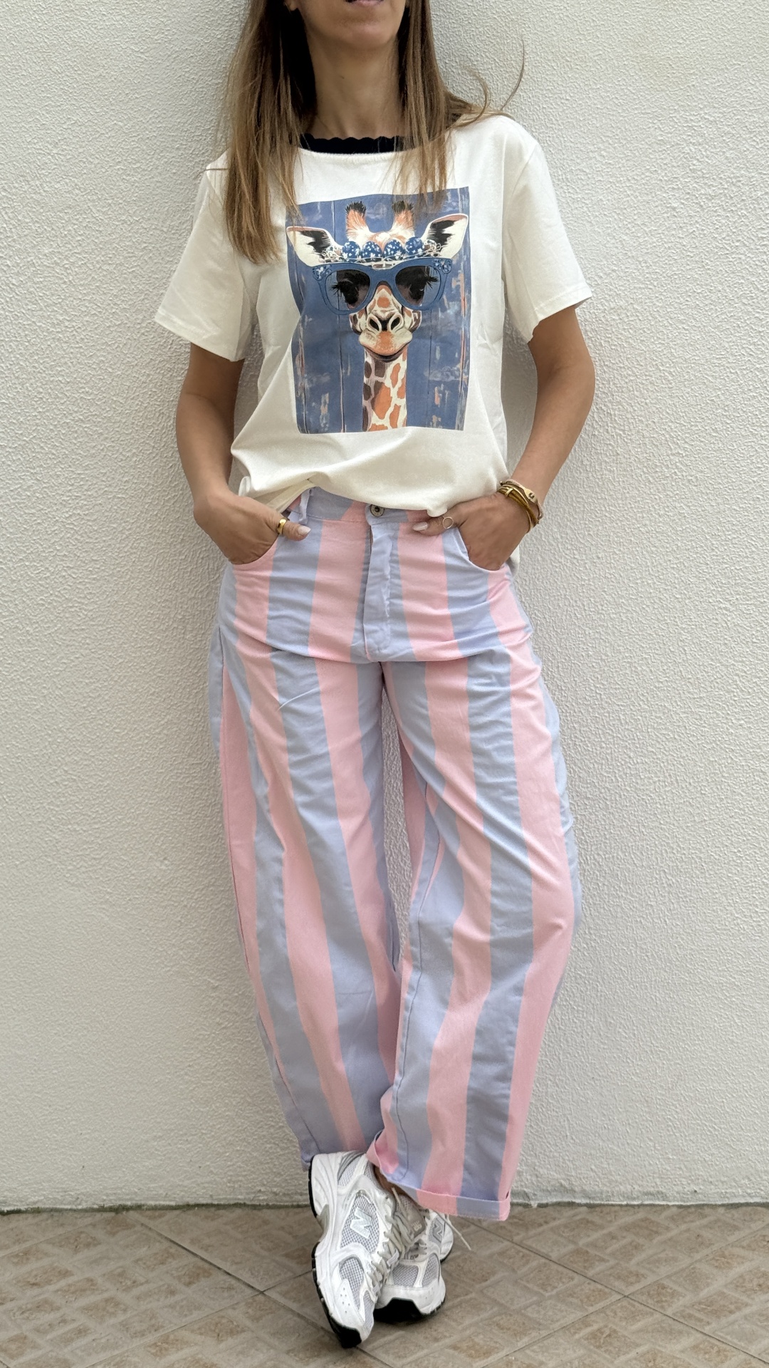 Pessoa com t-shirt estampada de girafa e calças largas riscas rosa e azul claro