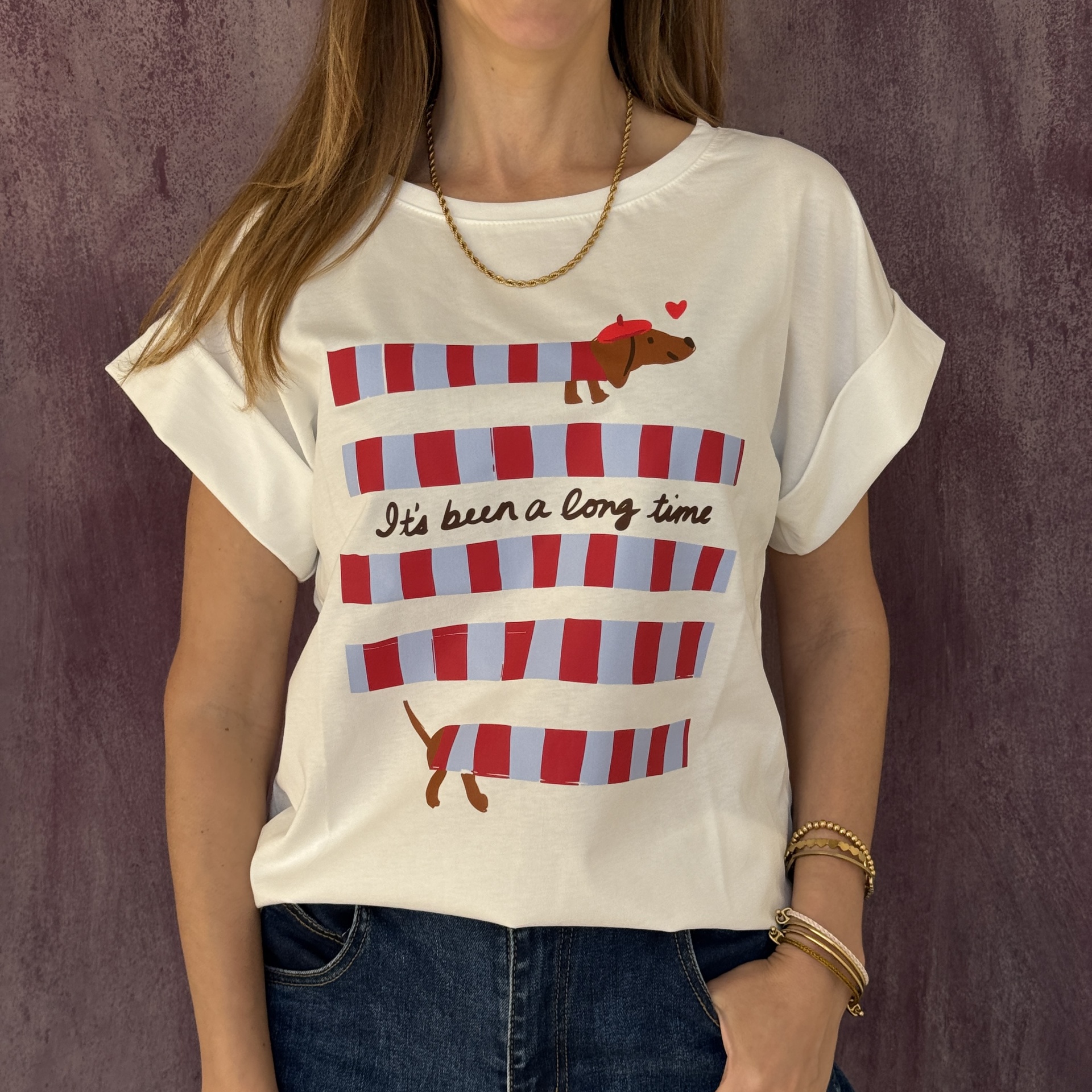 T-shirt branca com estampa colorida e jeans azul escuro.