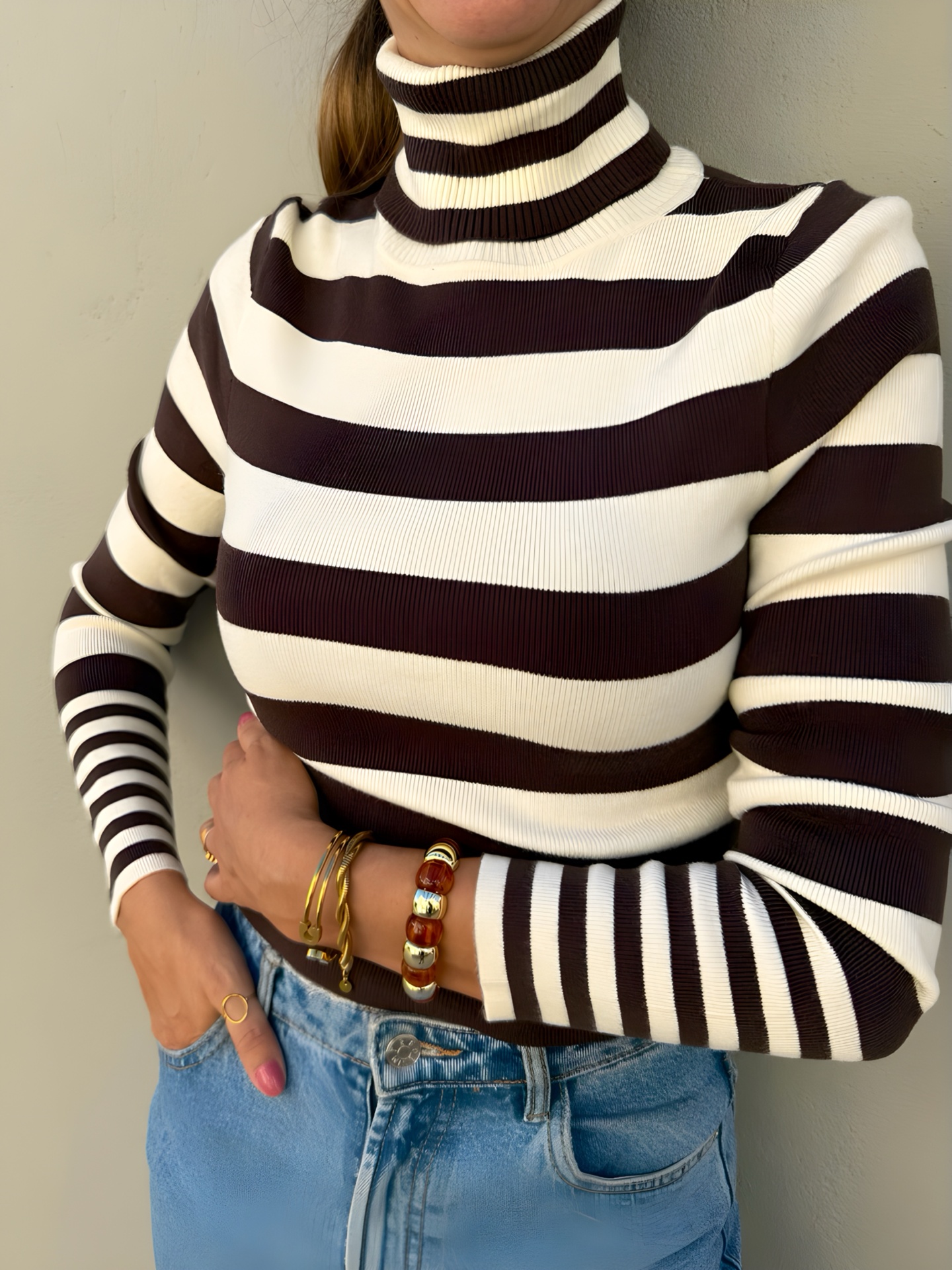 Camisola de gola alta riscada castanha e branca com calças de ganga.
