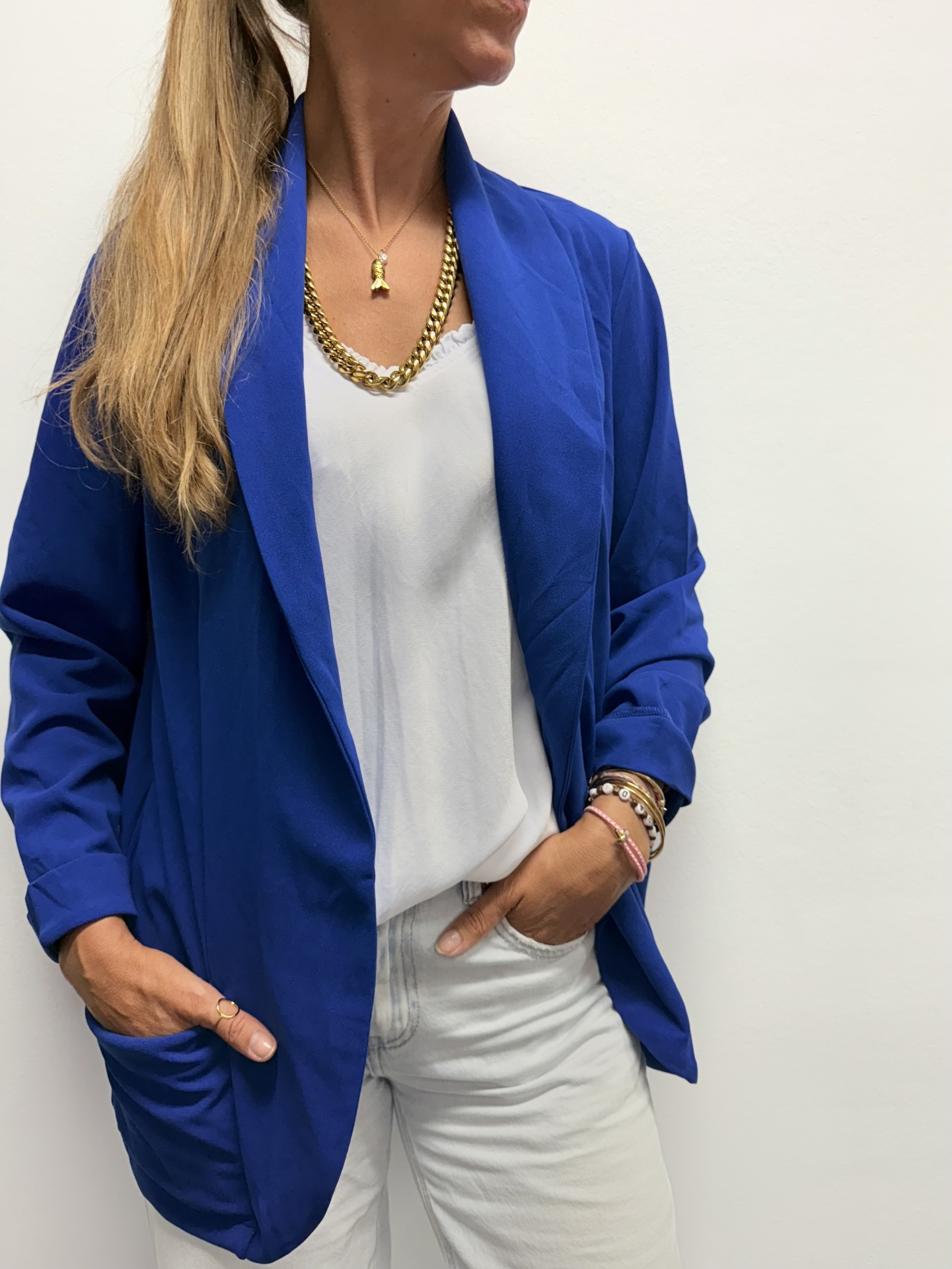 Mulher com blazer azul royal, camisola branca e calças brancas