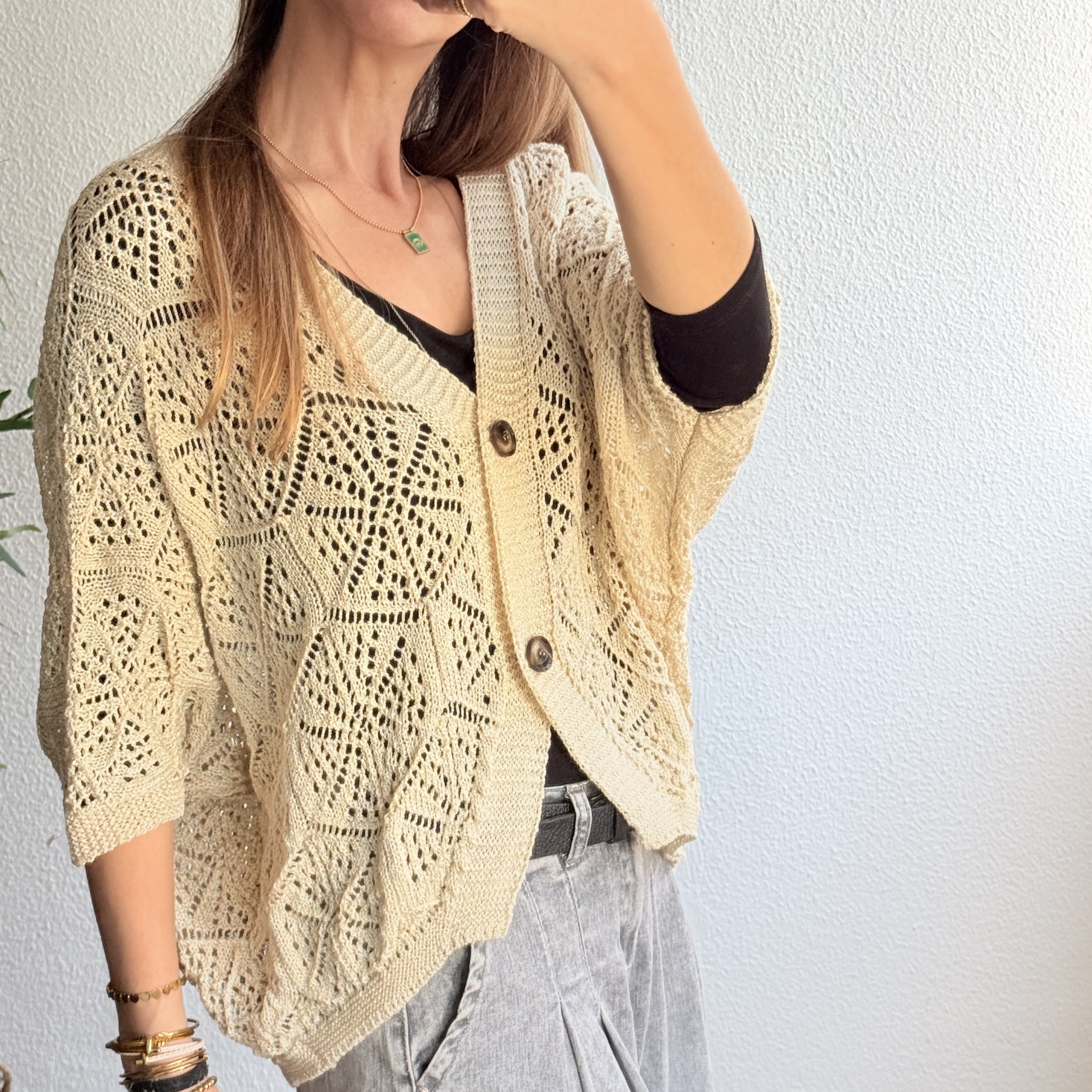 Cardigan bege claro de malha aberta com padrão geométrico e botões castanhos