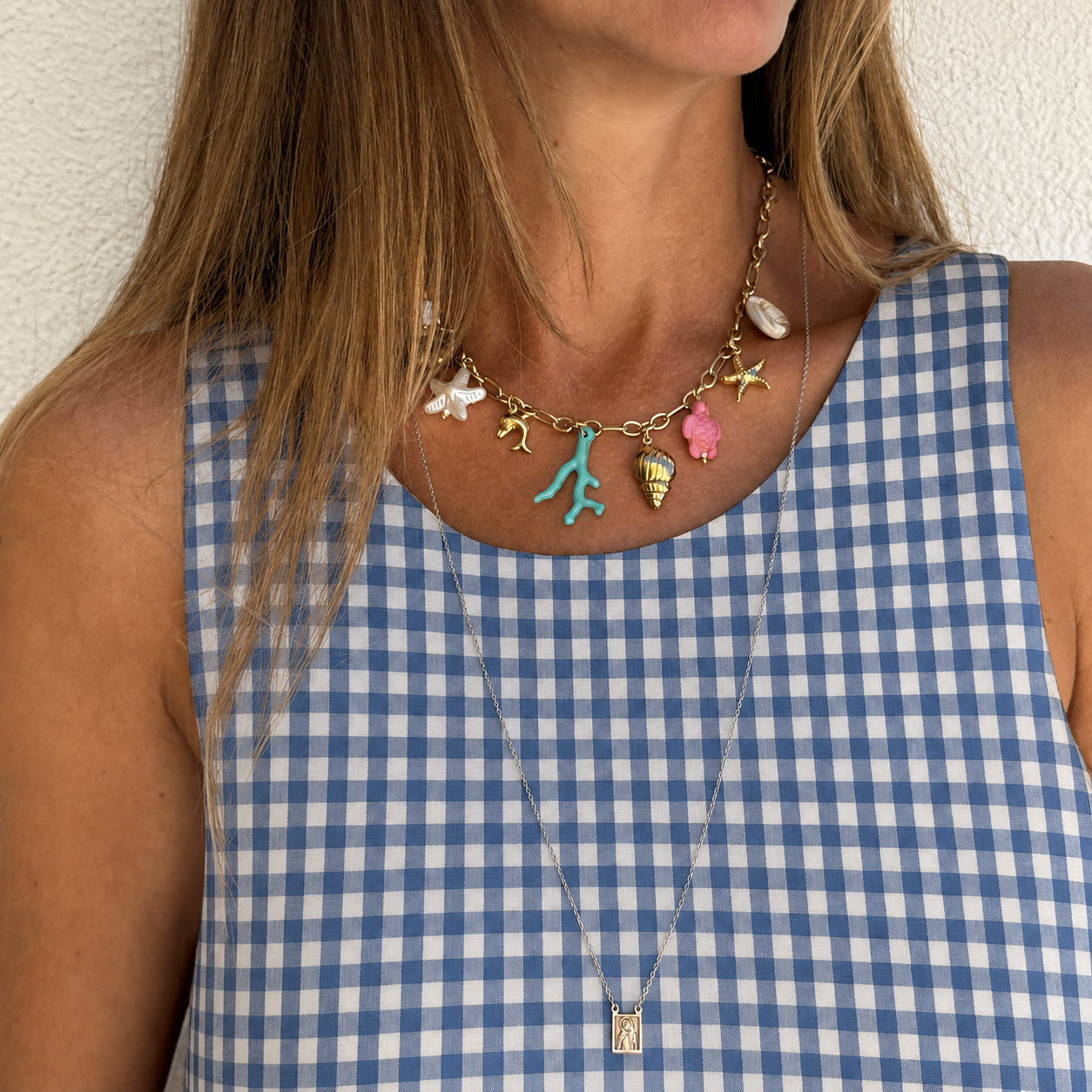 Colar dourado com pendentes coloridos e vestido quadrillé azul e branco