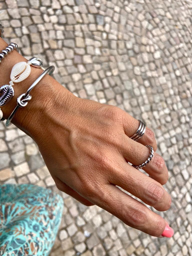 Mão feminina com anéis e pulseiras sobre calçada portuguesa