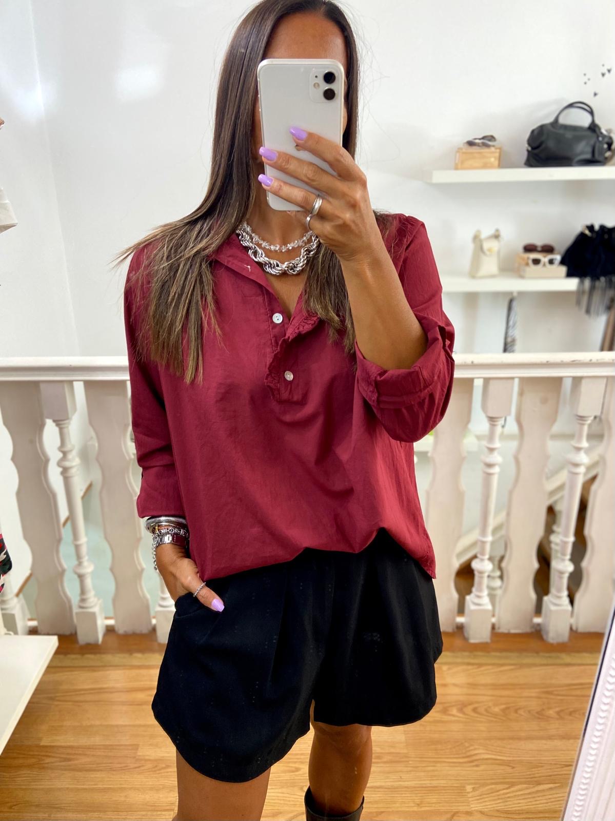 Pessoa com camisa vinho e calções pretos em interior com corrimão branco.