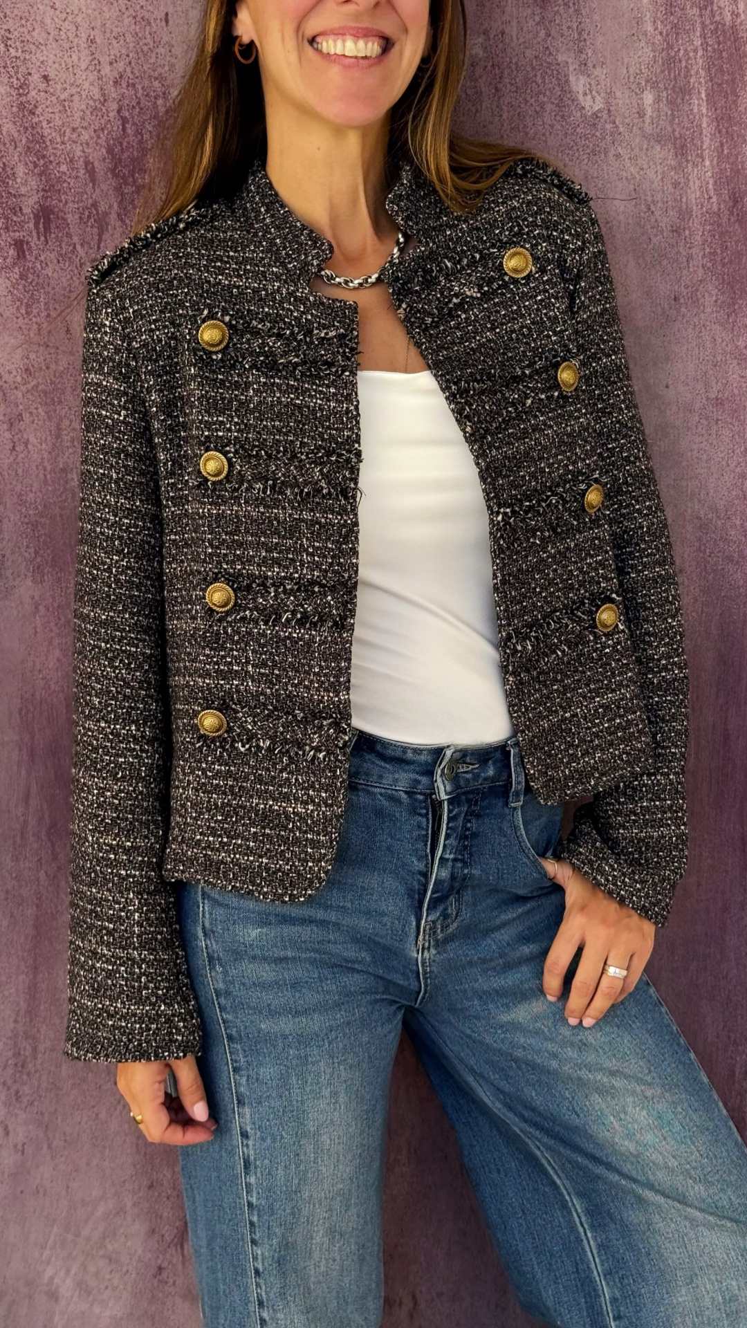 Casaco tweed cinza com botões dourados e franjas, mulher com t-shirt branca e ganga azul