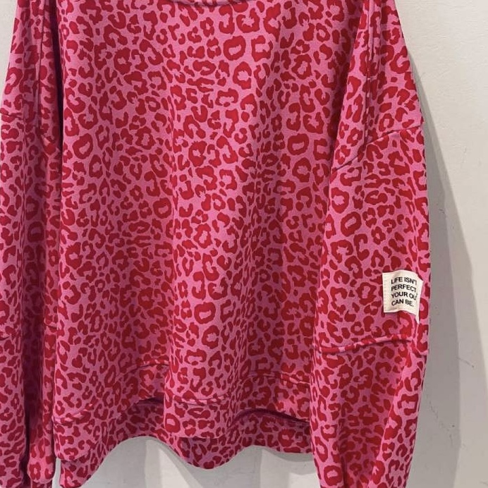 Sweatshirt rosa e vermelha com padrão leopardo e etiqueta na manga.