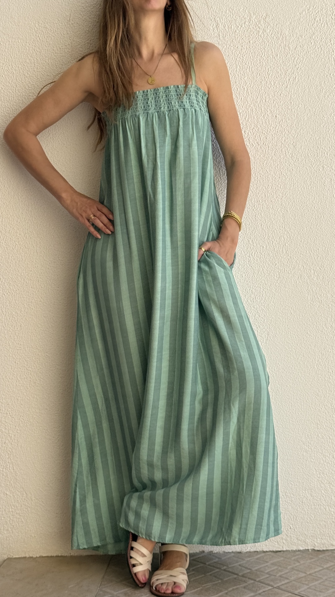 Vestido comprido verde com padrão riscado vertical e sandálias creme