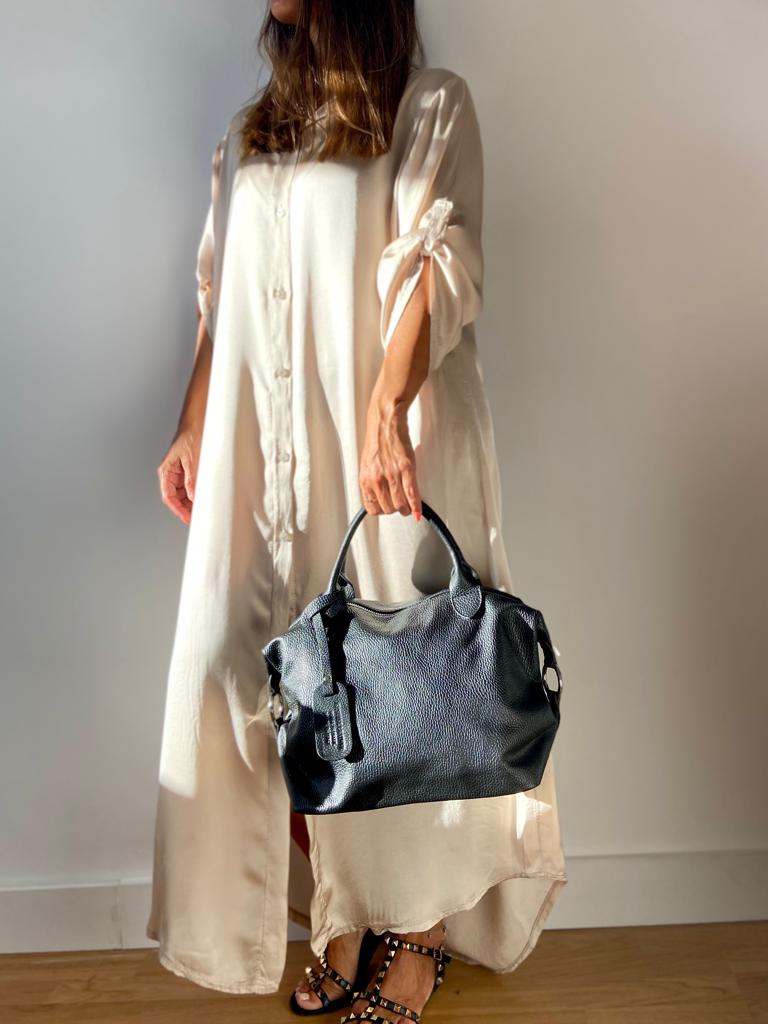 Mulher com vestido creme e mala de mão preta com textura de pele