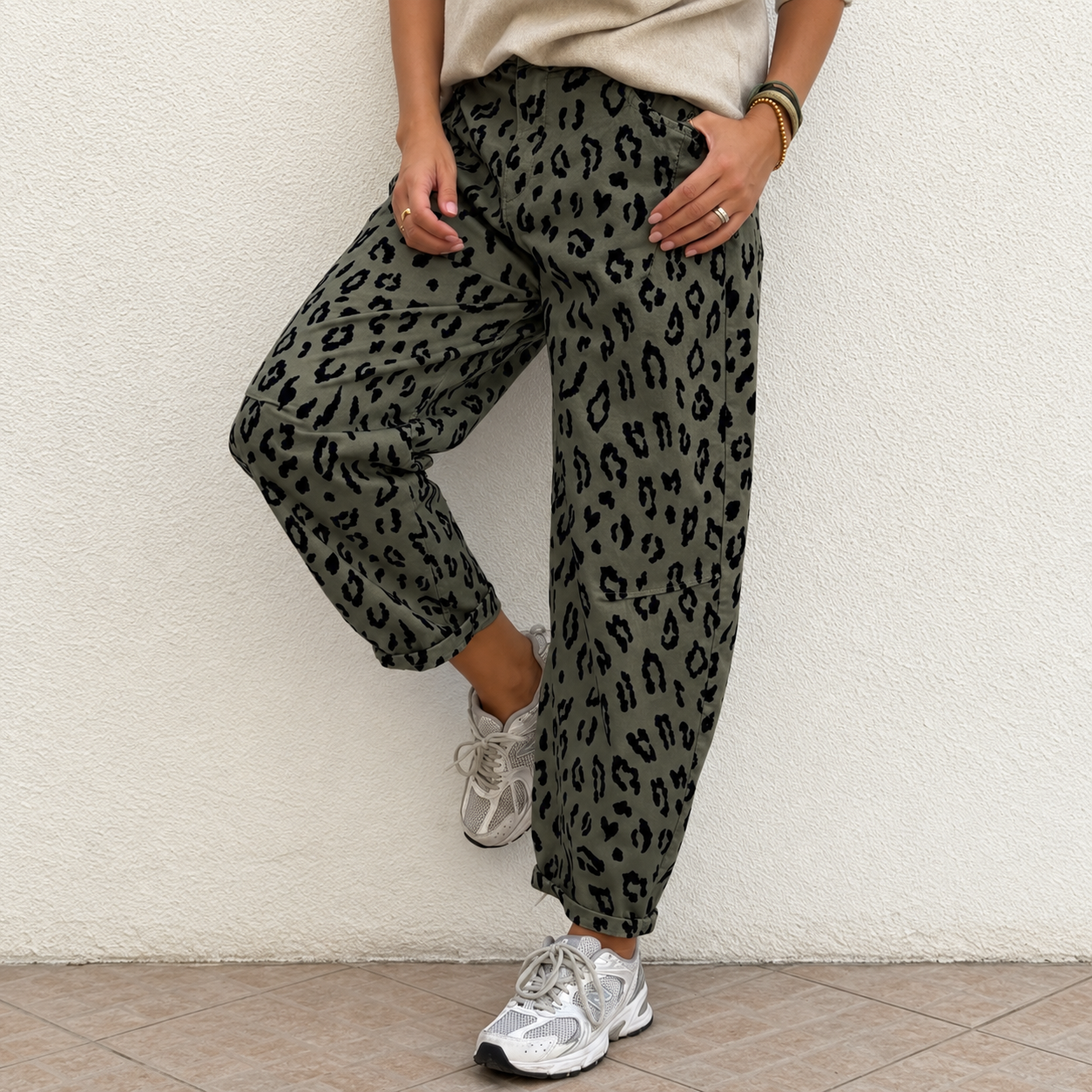 Calças verdes com padrão animal print preto usadas com ténis brancos e t-shirt bege