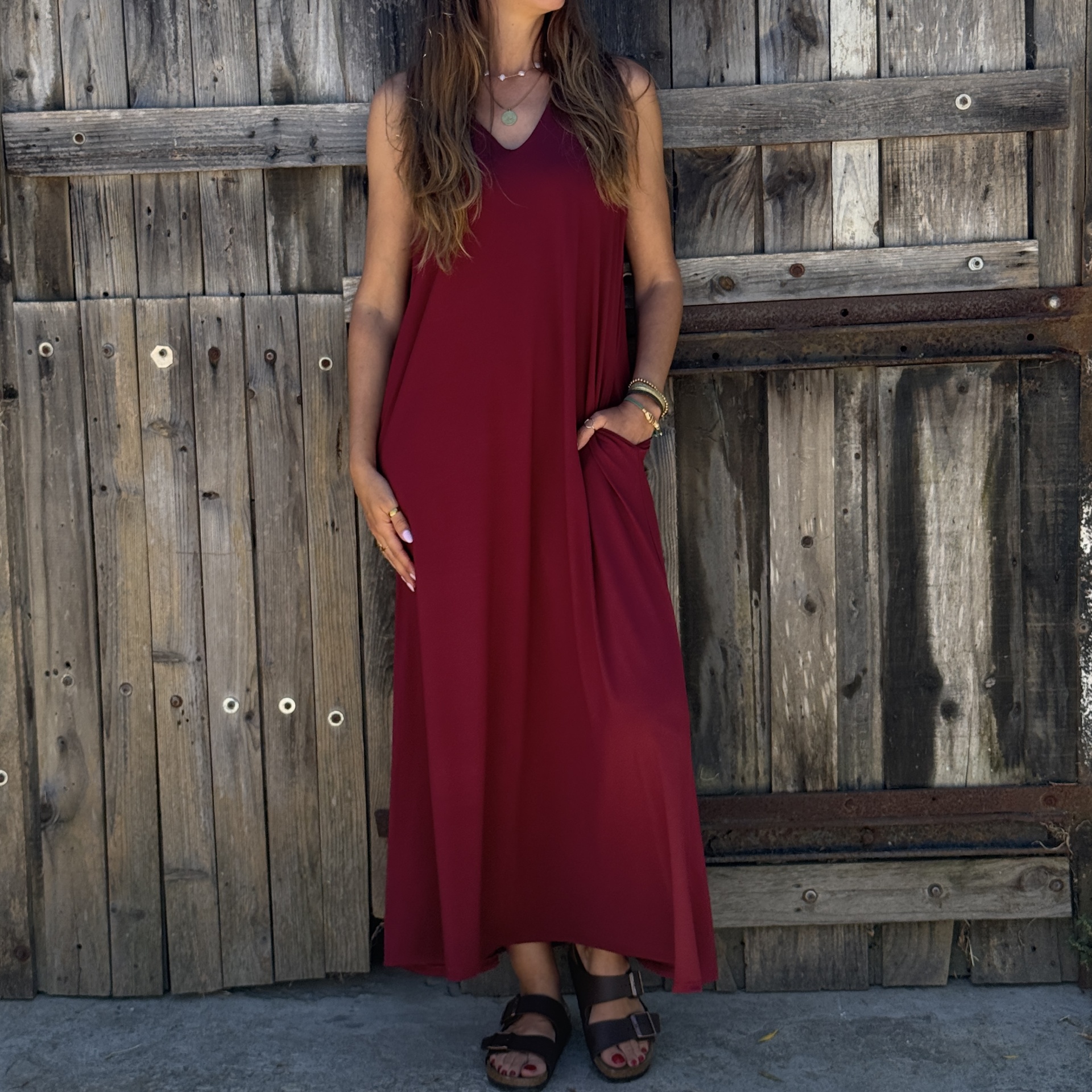 Vestido comprido vinho sem mangas com decote em V usado por mulher