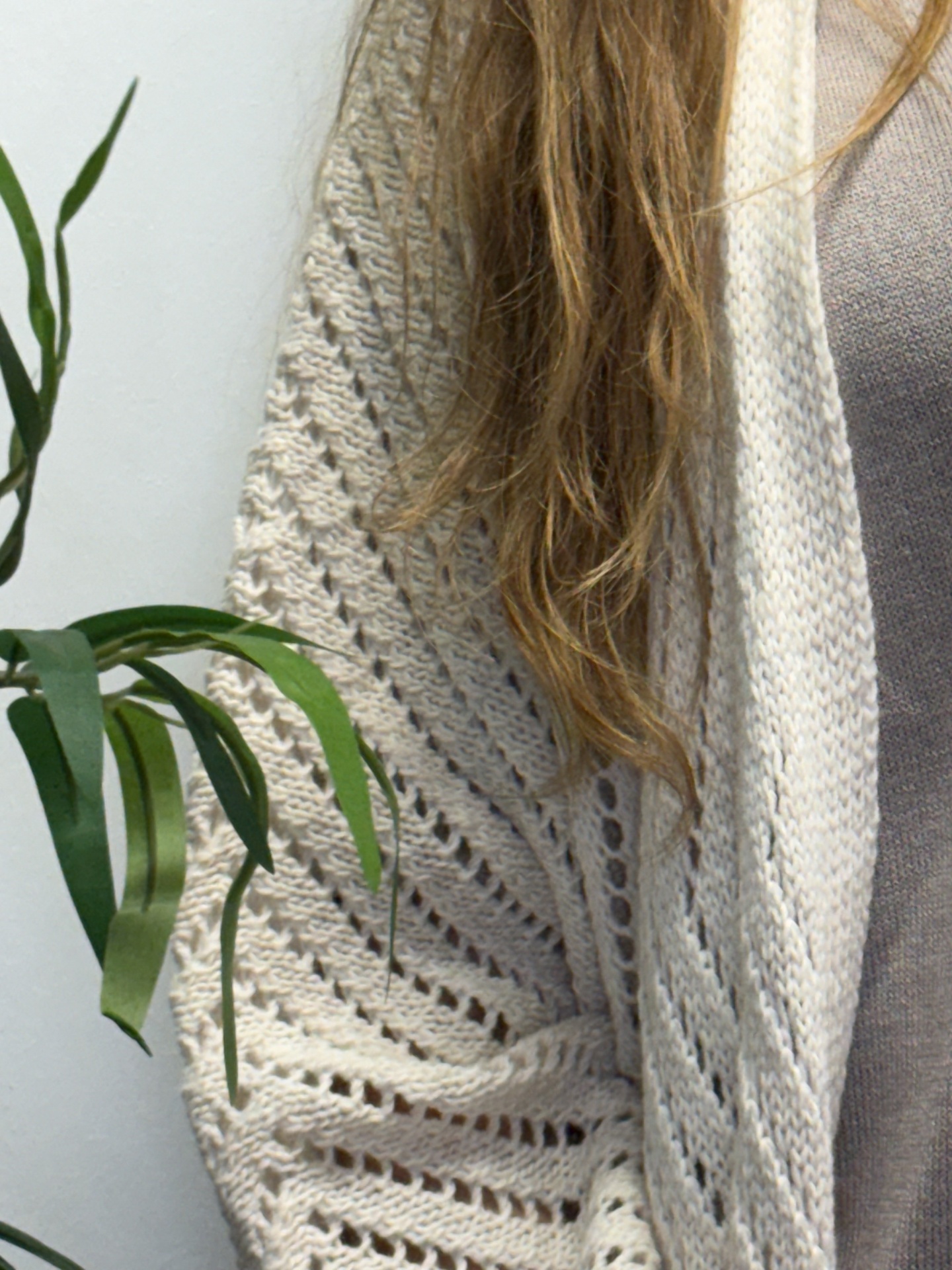 Xale creme de malha com padrão ajourado usado por pessoa com cabelo comprido castanho claro.