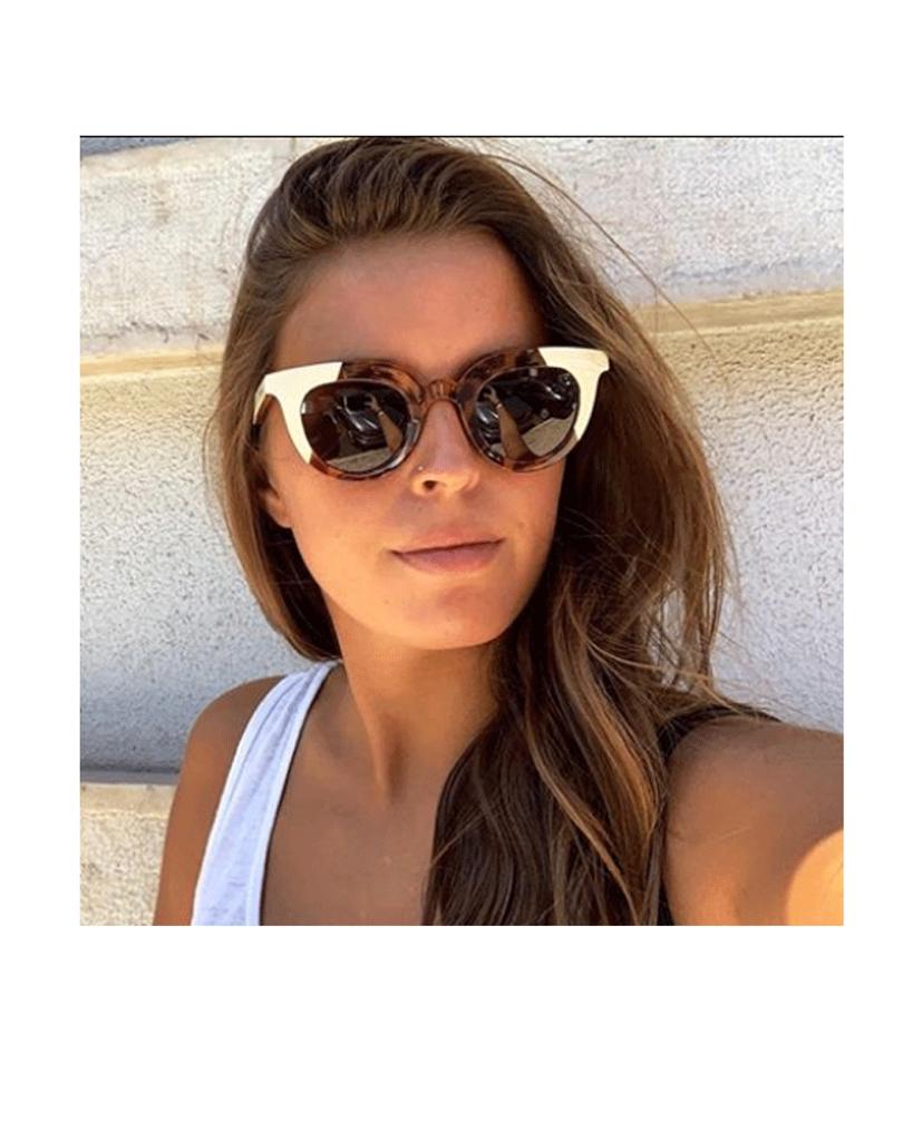 Mulher a usar óculos de sol com armação de padrão tartaruga e abas pretas.