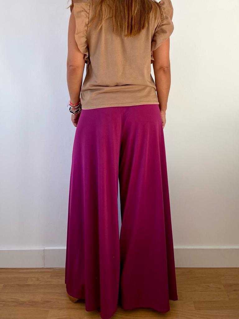 Calças largas roxas e t-shirt bege vistas de costas