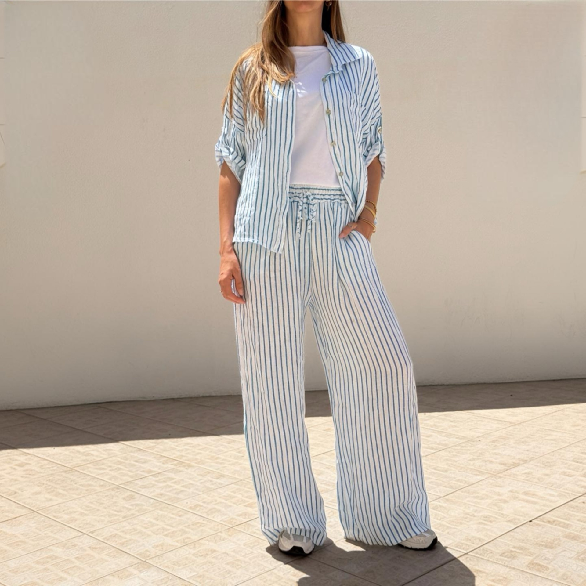 Mulher vestindo conjunto riscado azul e branco e T-shirt branca com calçado desportivo.