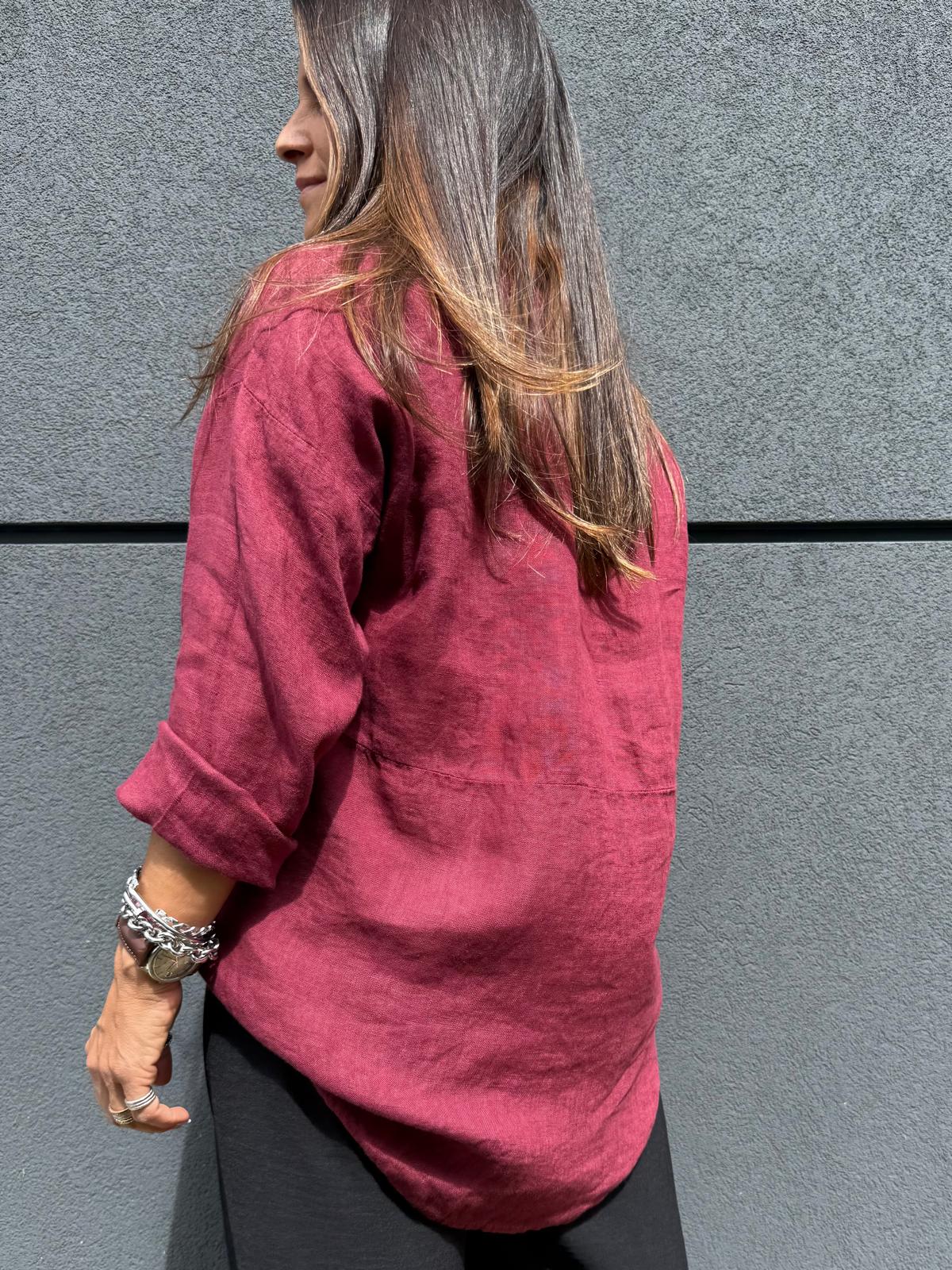 Camisa vinho de tecido liso vista de costas com pulseiras prateadas