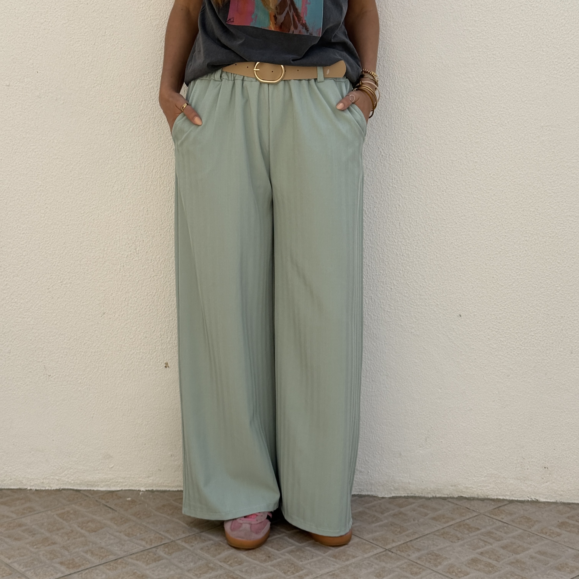 Calças largas verdes claras com cinto bege e chão com padrão quadrado cinza