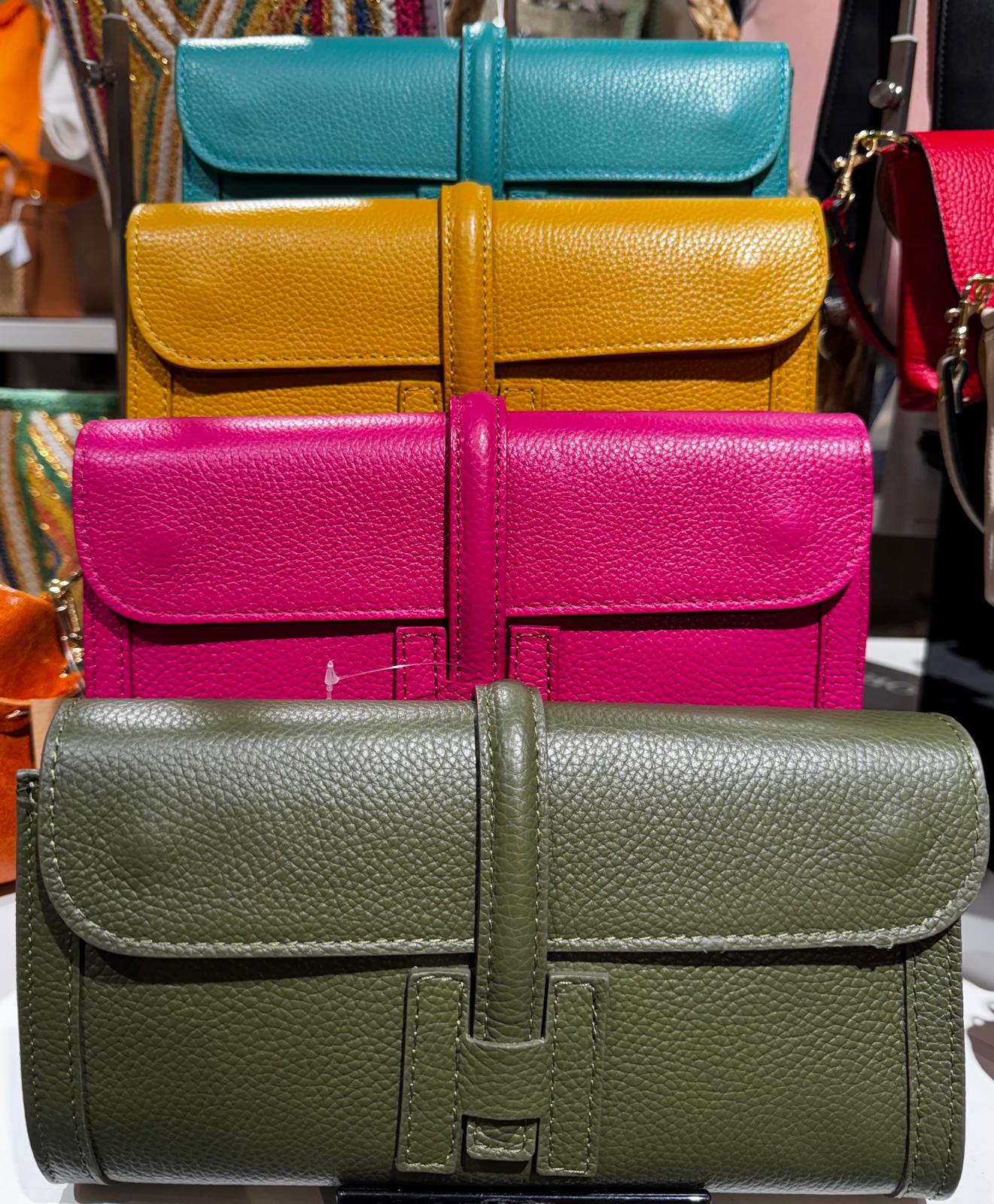 Conjunto colorido de carteiras de mão em couro texturizado empilhadas no expositor