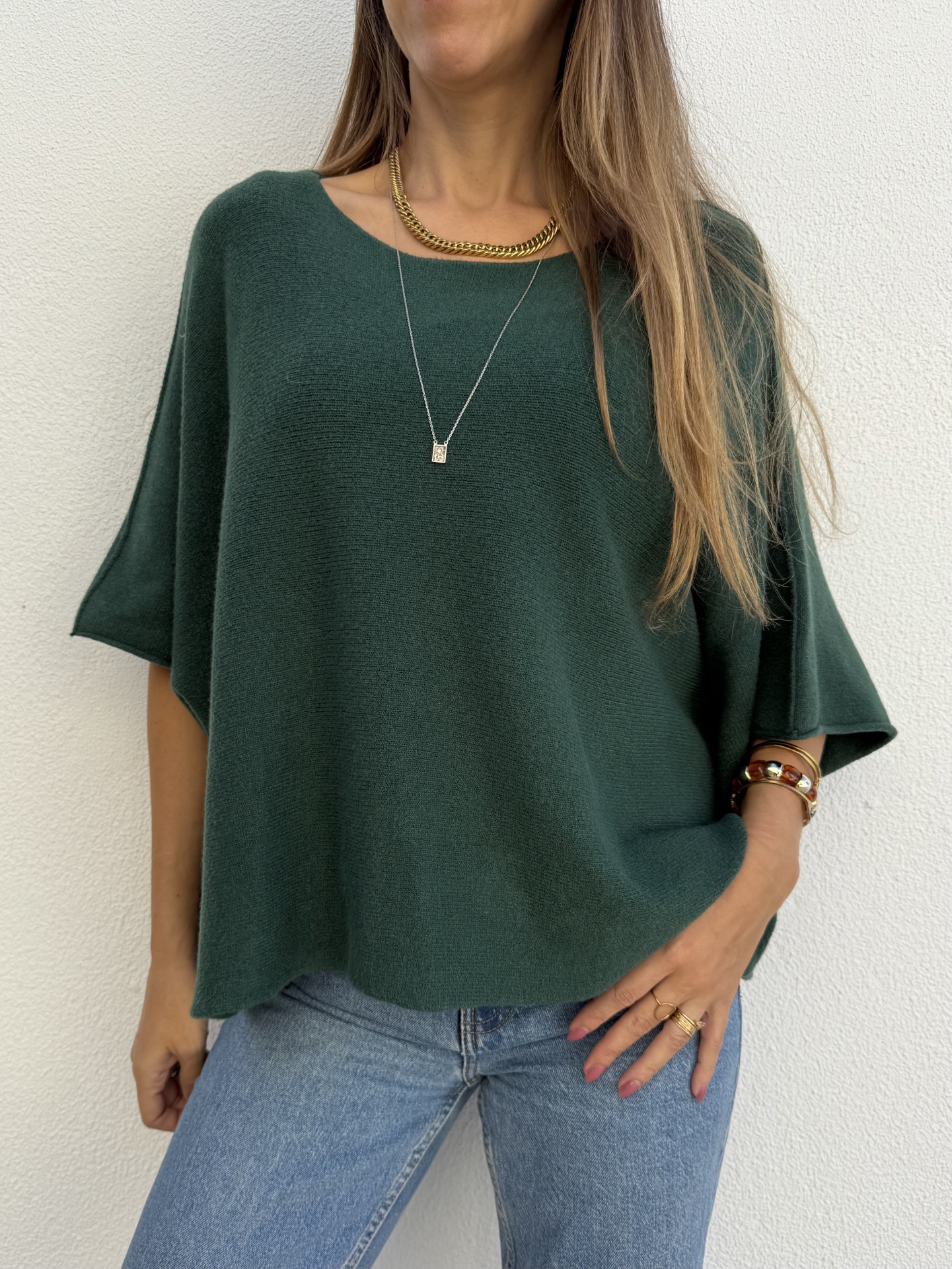 Camisola de malha verde escura com jeans azul claro e acessórios dourados