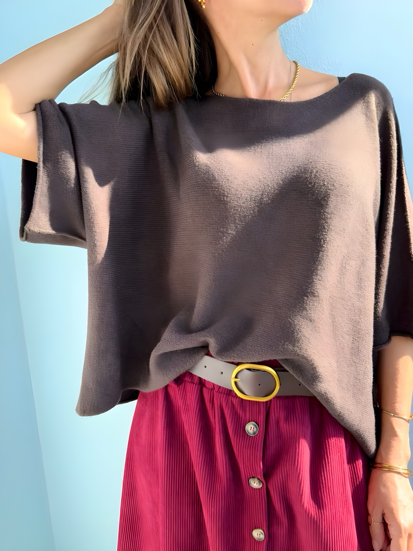 Mulher vestida com camisola castanha, saia rosa e cinto branco com fivela dourada