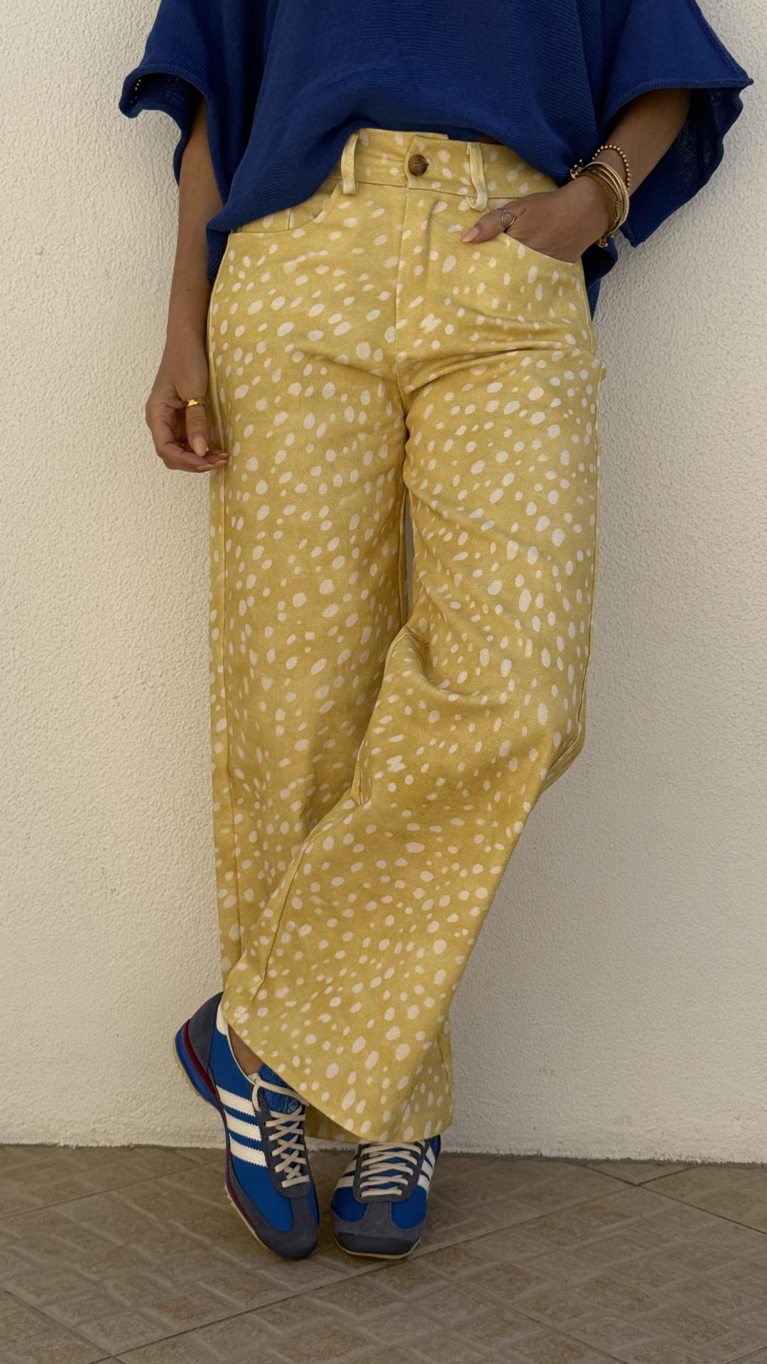 Calças amarelas manchadas com camisola azul e sapatilhas azuis