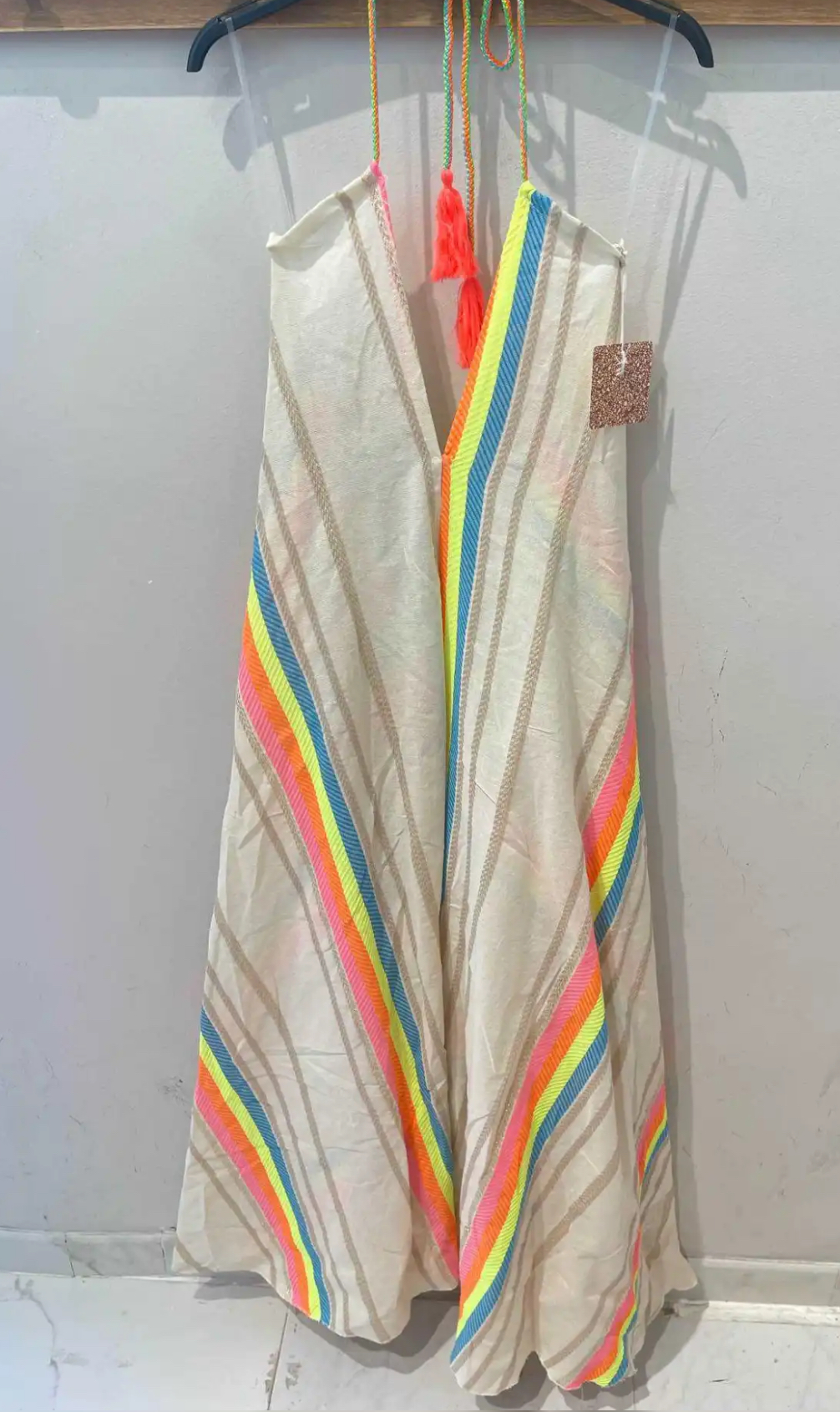 Vestido comprido colorido pendurado numa parede branca