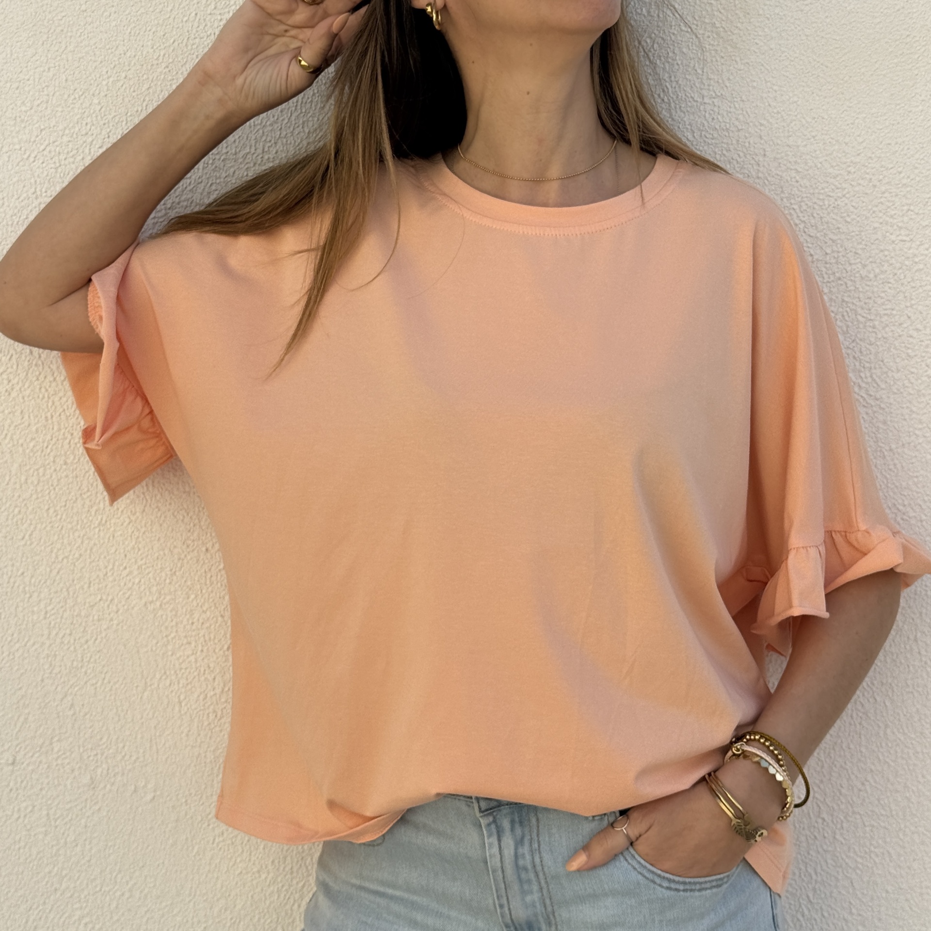 Camisola rosa clara com folhos e acessórios dourados