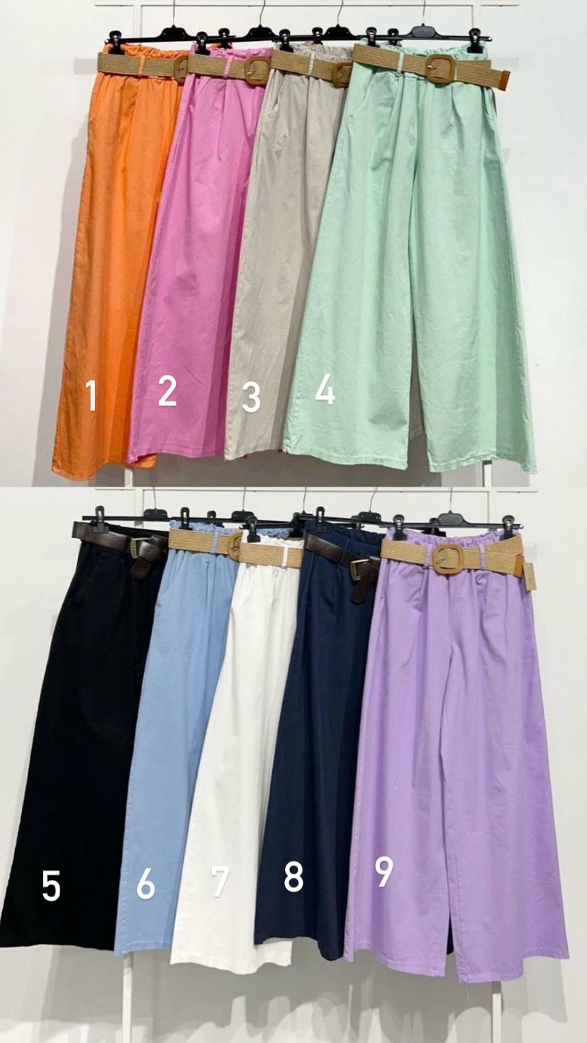 Dez saias compridas coloridas com cintos castanhos penduradas em cabides numa estante branca.